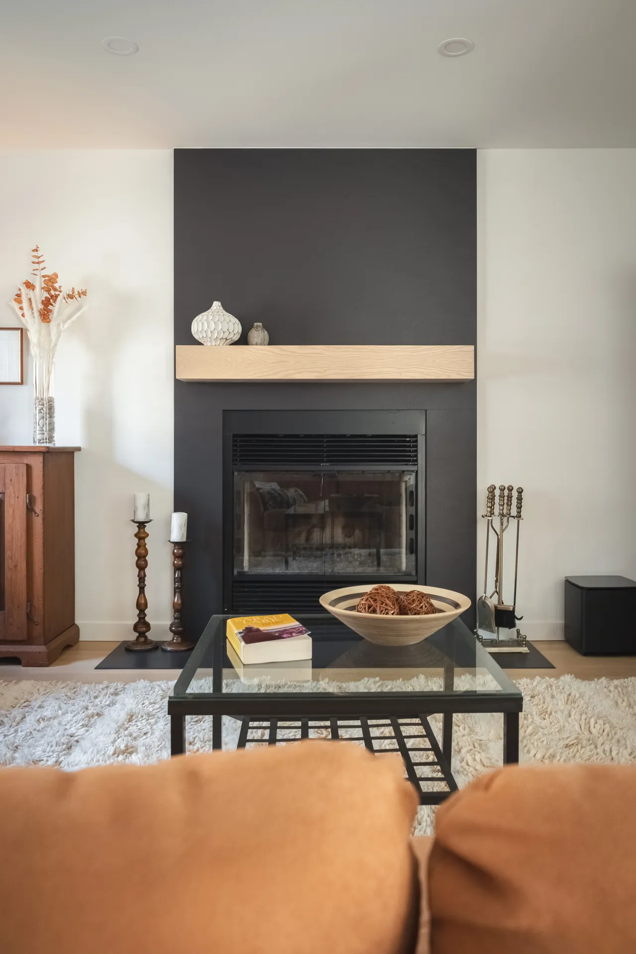Foyer moderne avec foyer encadré de panneaux gris anthracite, tablette en bois naturel, et accessoires de décoration minimalistes