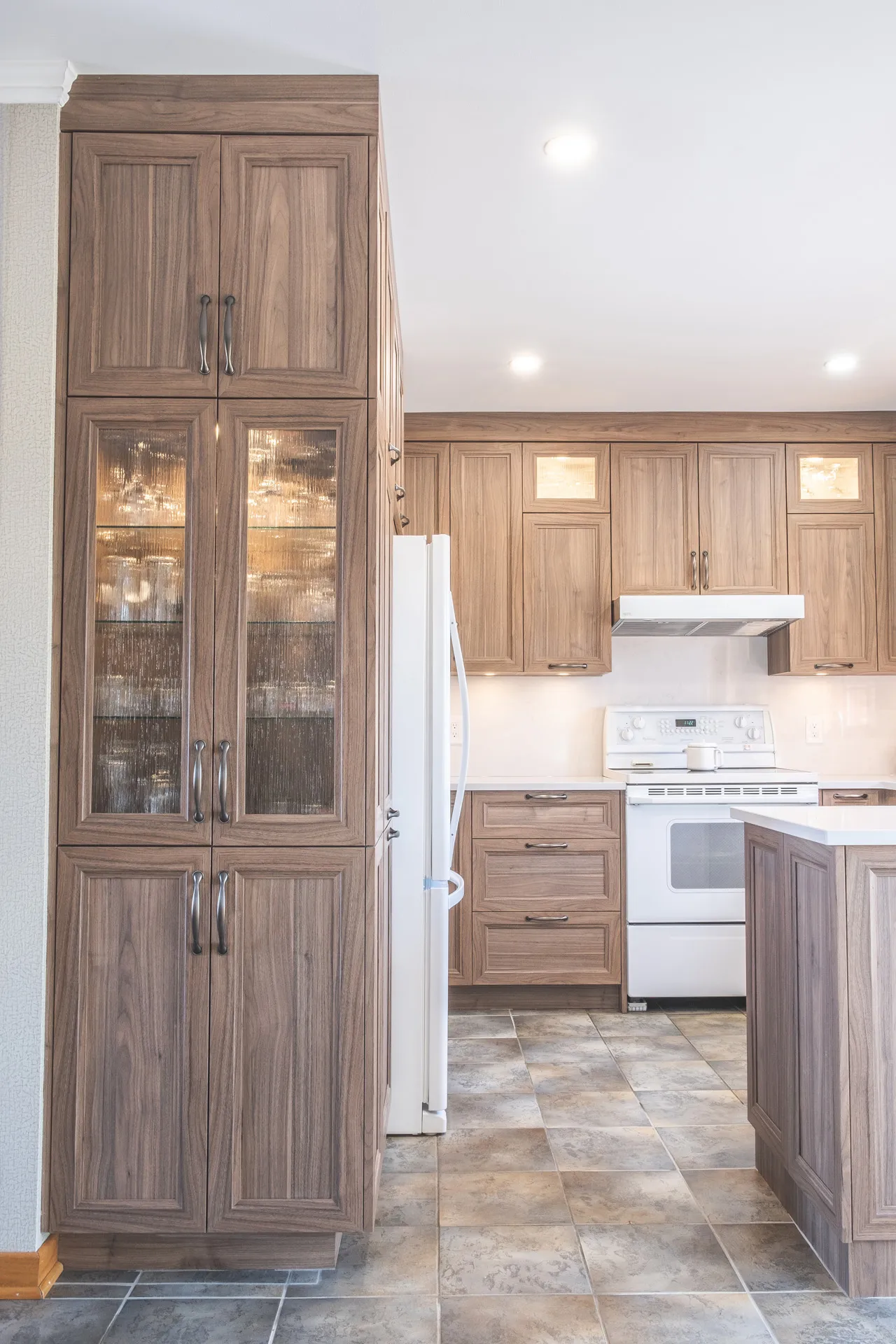 Nadon kitchen Rosemère: textured walnut cabinets, stone countertop, center island, white backsplash, white appliances