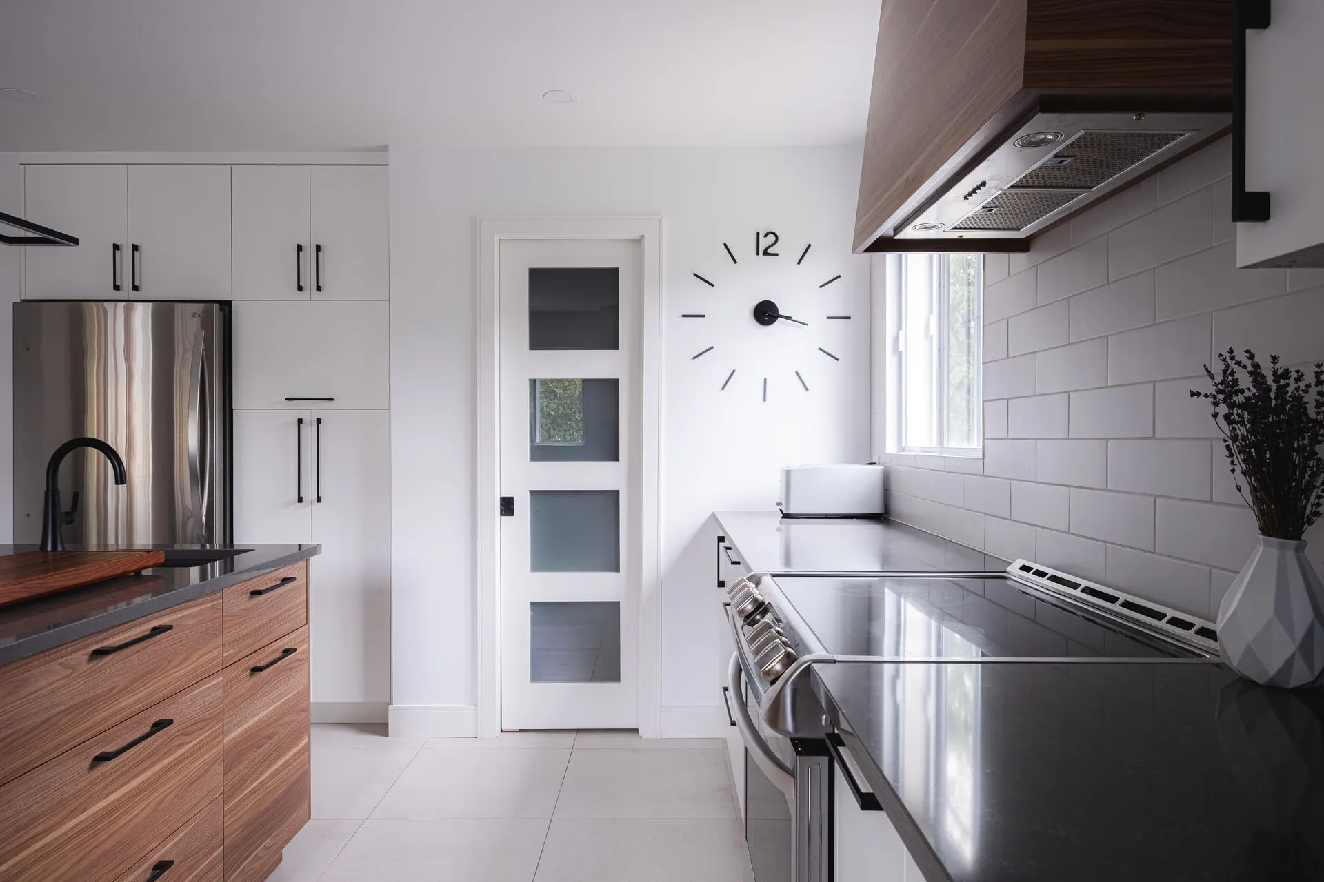 Modern Montreal kitchen: white and wood cabinets, grey countertop, island, white subway backsplash, stainless steel appliances