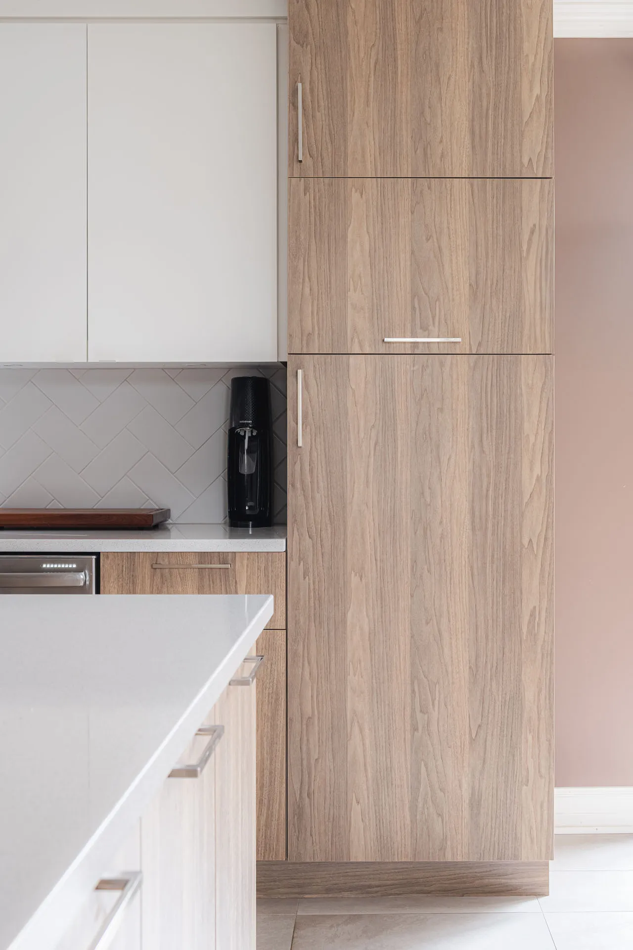 Modern Menuitech kitchen with natural wood cabinets, white countertop, grey subway backsplash and white island.