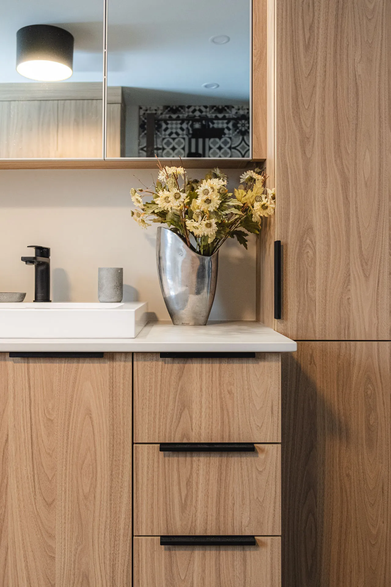 Robitaille bathroom with light wood cabinets, white countertop, framed mirror and black ceiling light fixture