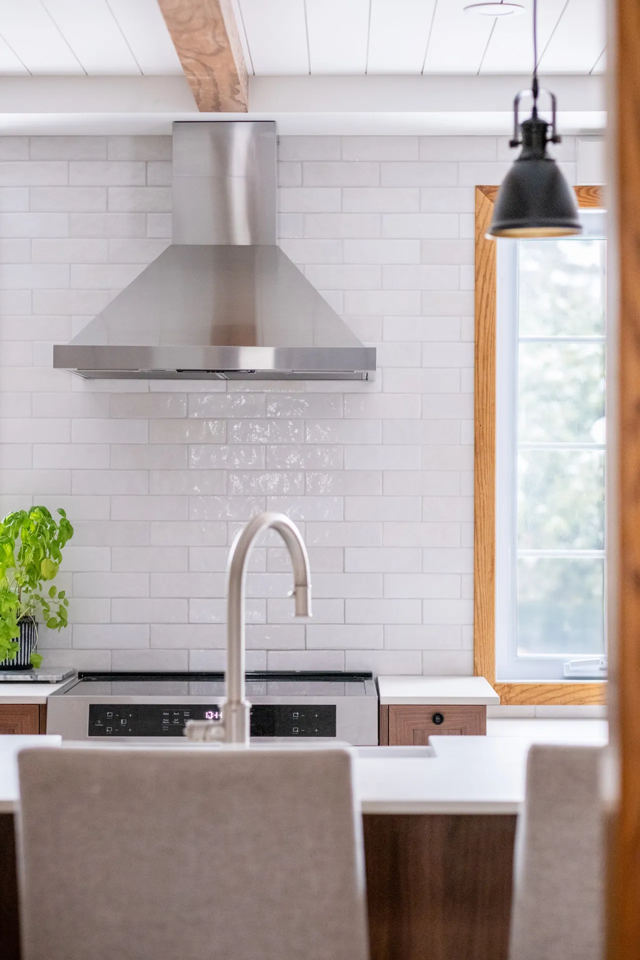Lemay kitchen Laval: light wood cabinets, black countertop, white subway backsplash, island, stainless steel hood, black pendant