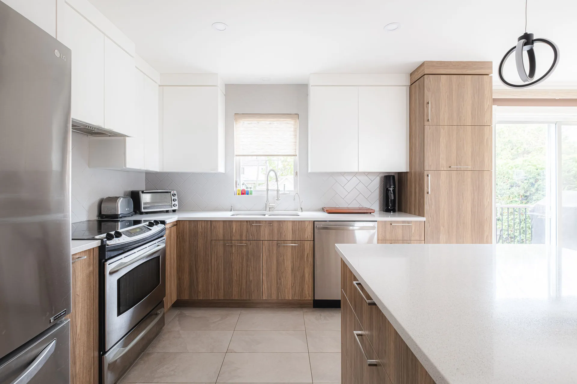 Modern Menuitech kitchen with natural wood cabinets, white countertops, grey herringbone backsplash and central island