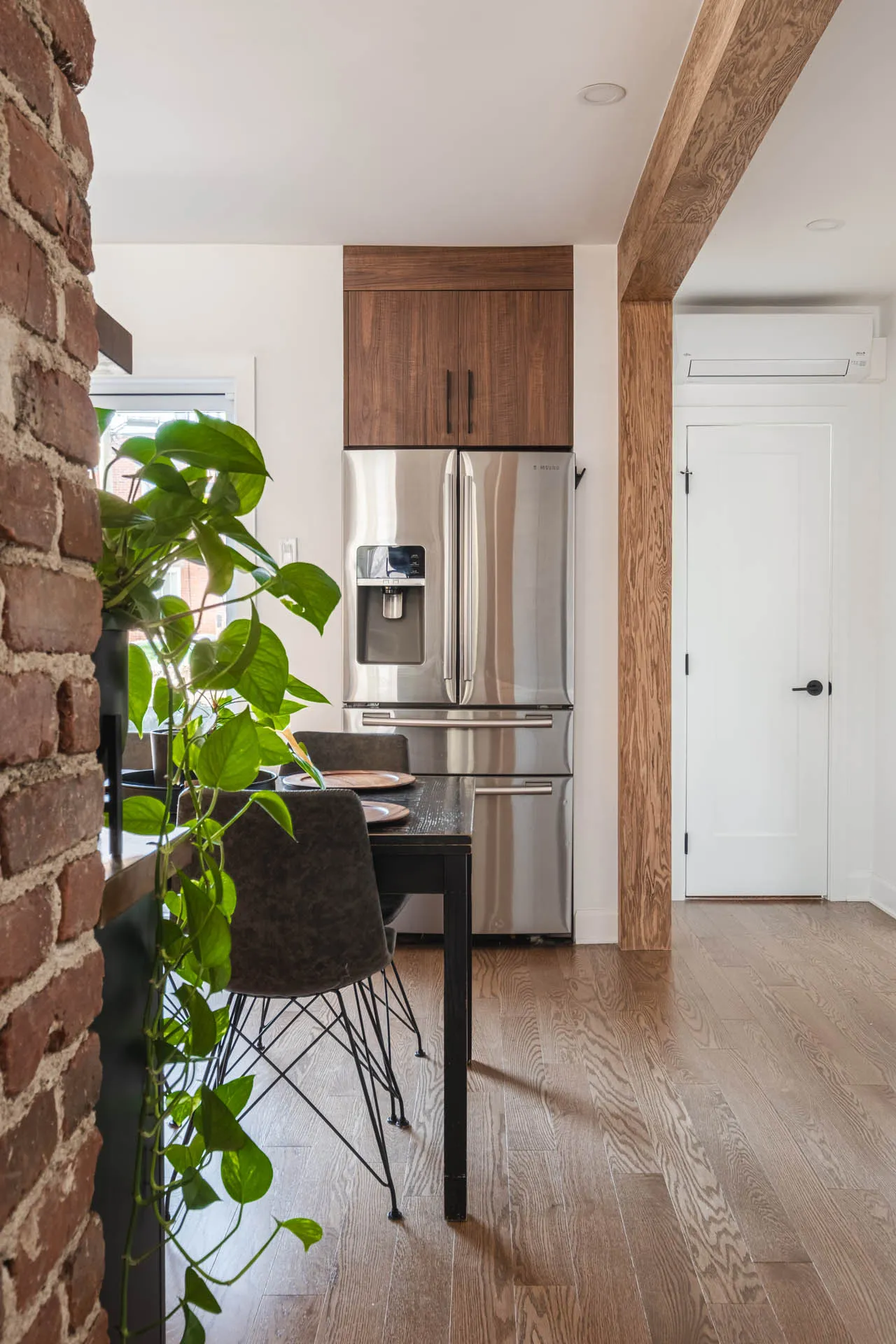 Florez Kitchen Montreal: walnut cabinets, stainless steel refrigerator, wood beam, red brick, light wood flooring