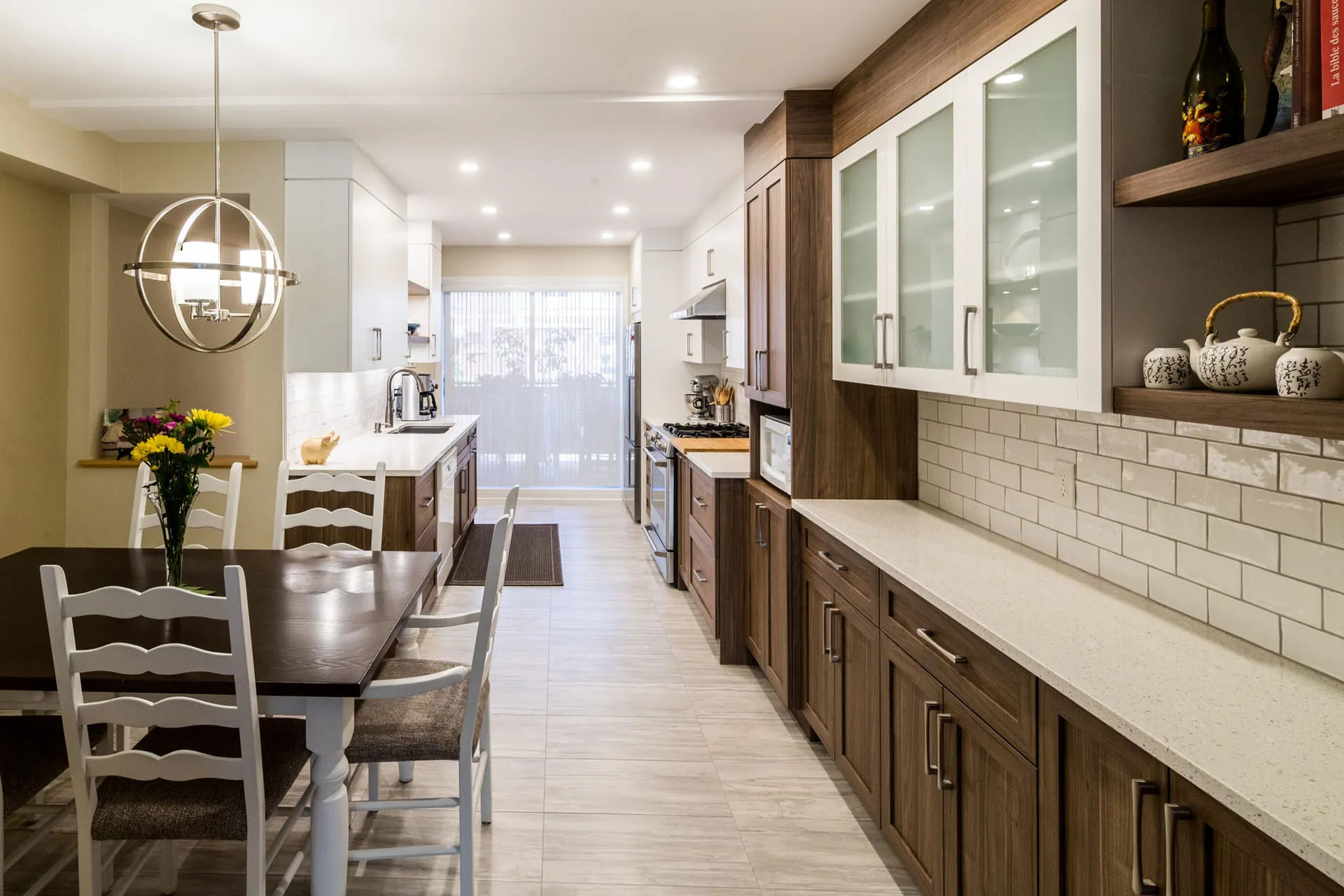Mathieu kitchen renovation in Montreal: dark wood cabinetry with glass doors, white countertop, subway tile backsplash, central island, spherical pendant light