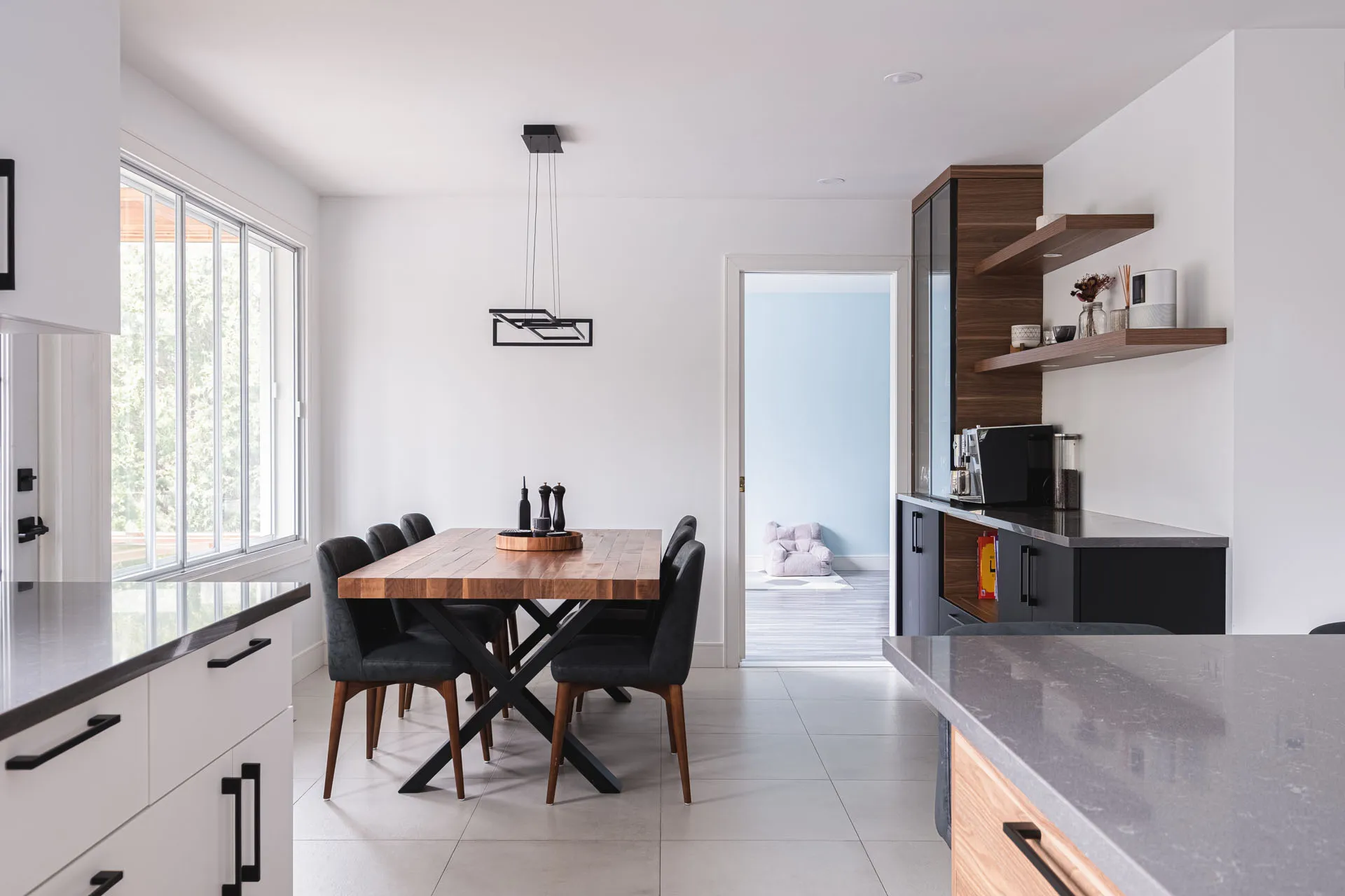 Modern Menuitech kitchen: white and wood cabinets, gray countertop, wood island table, black chairs, wall shelves