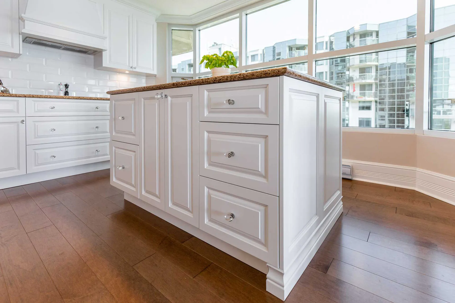 McDuff kitchen Repentigny: white framed cabinet doors, brown granite countertop, central island, white subway tile backsplash