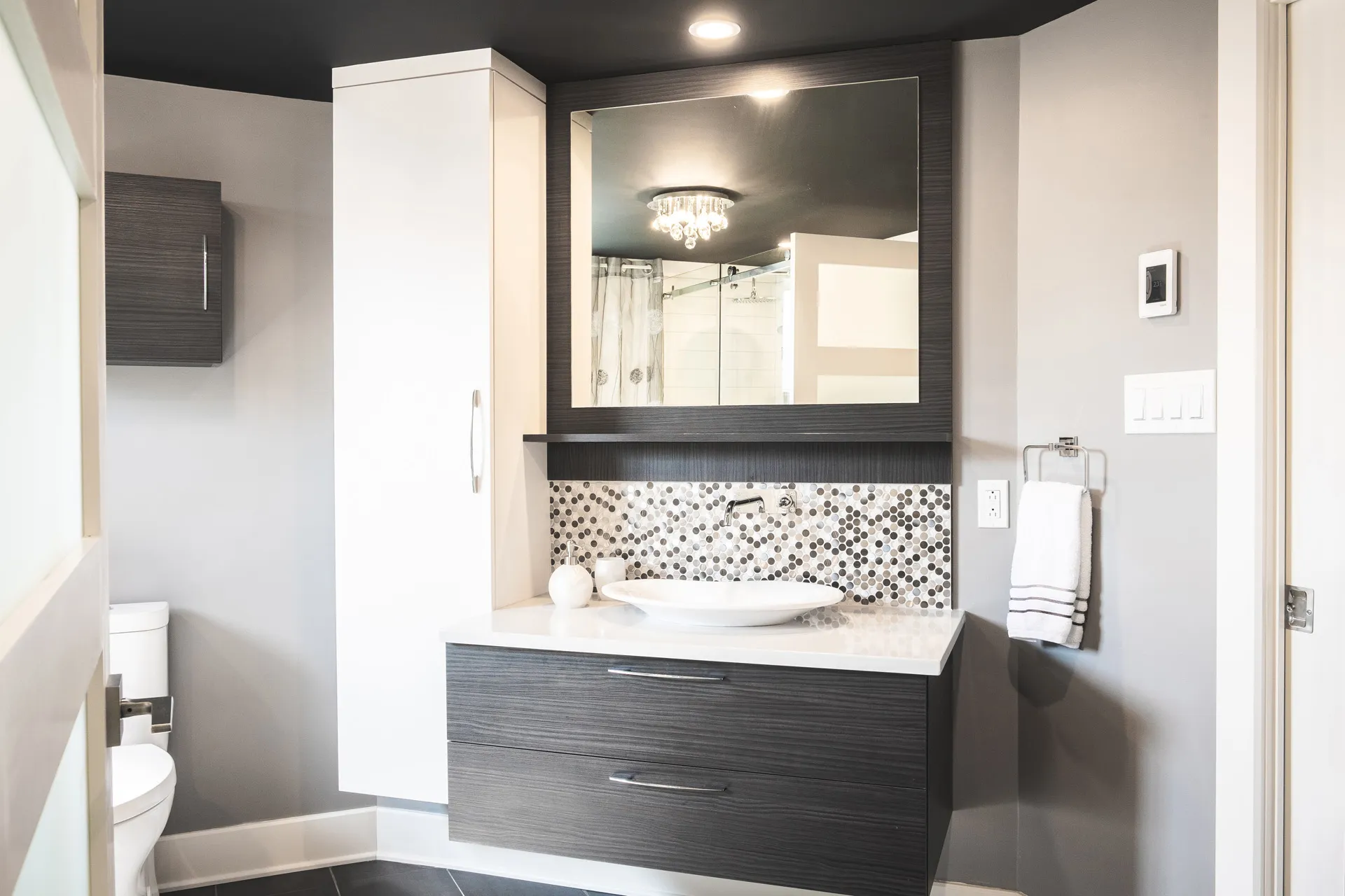 Pagé bathroom Laval: textured grey vanity, white countertop, grey and white mosaic backsplash, framed mirror