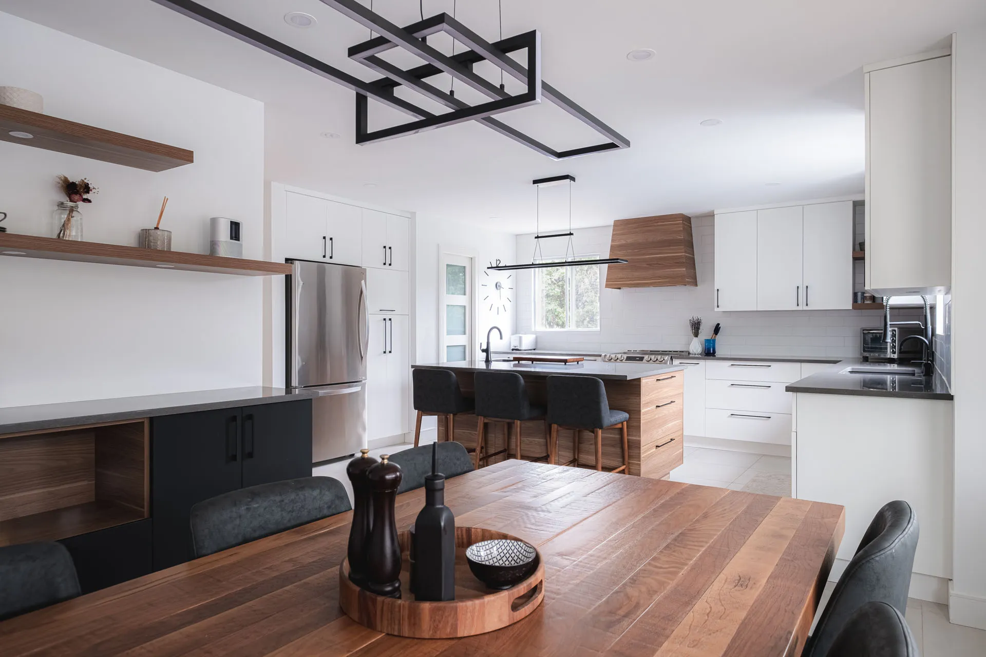 Modern white and wood kitchen with walnut island, black countertops, grey backsplash and geometric pendant lights