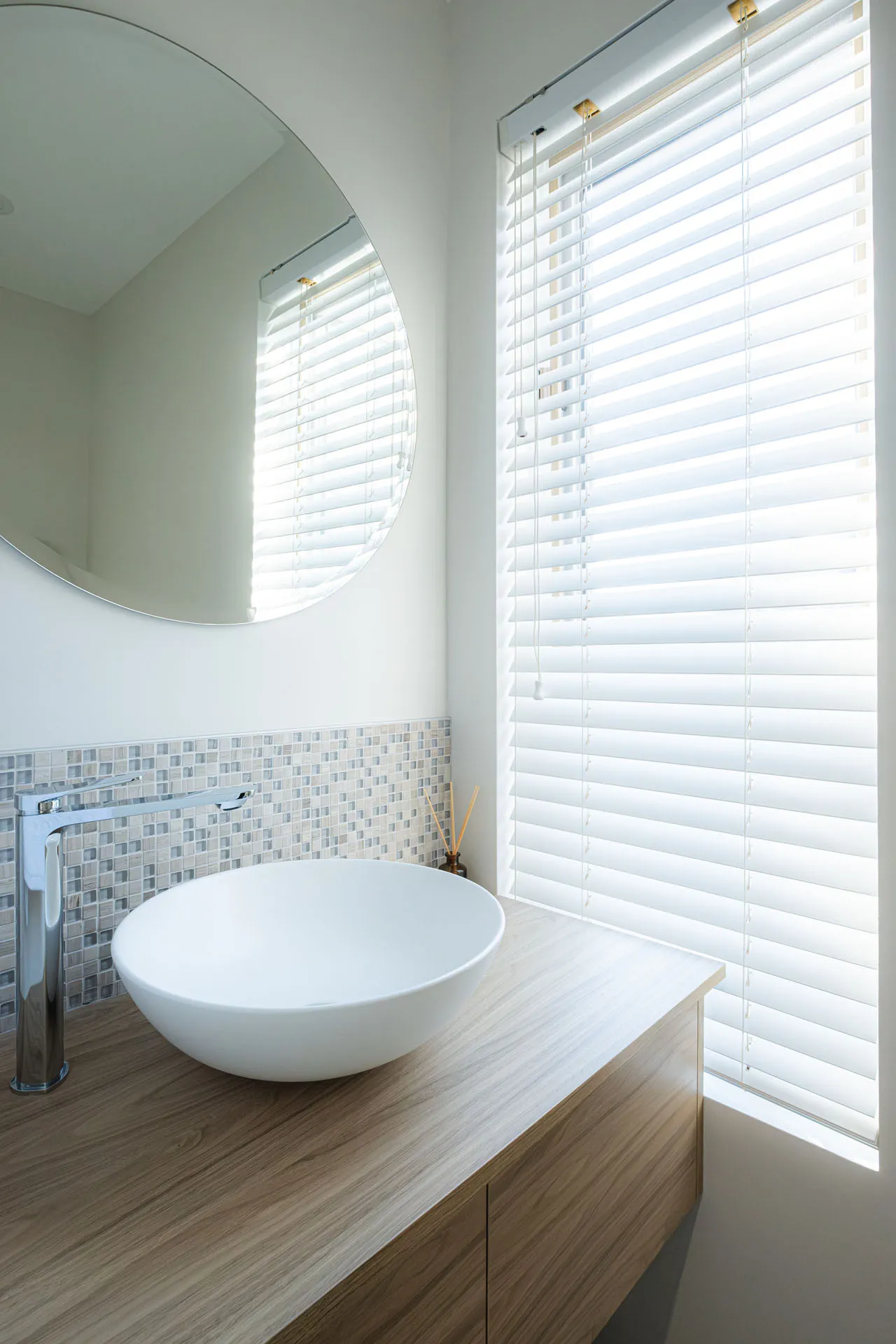 Salle de bain Menuitech Rosemère : vanité bois, comptoir clair, lavabo blanc rond, miroir circulaire, dosseret carrelage gris