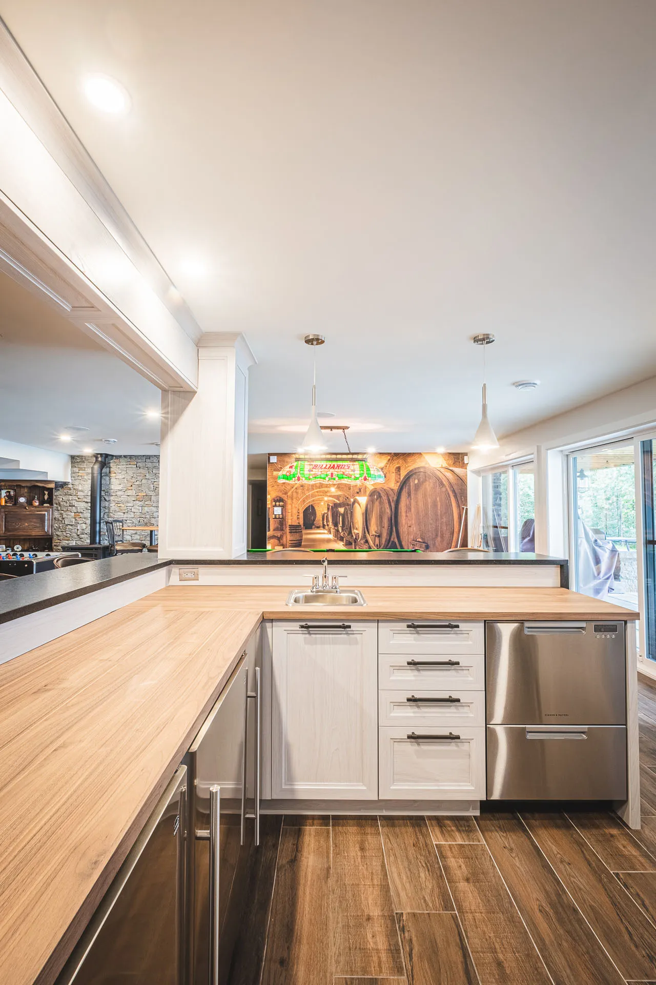 Modern kitchen with white cabinets, natural wood countertop, central island, tile backsplash, stainless steel appliances