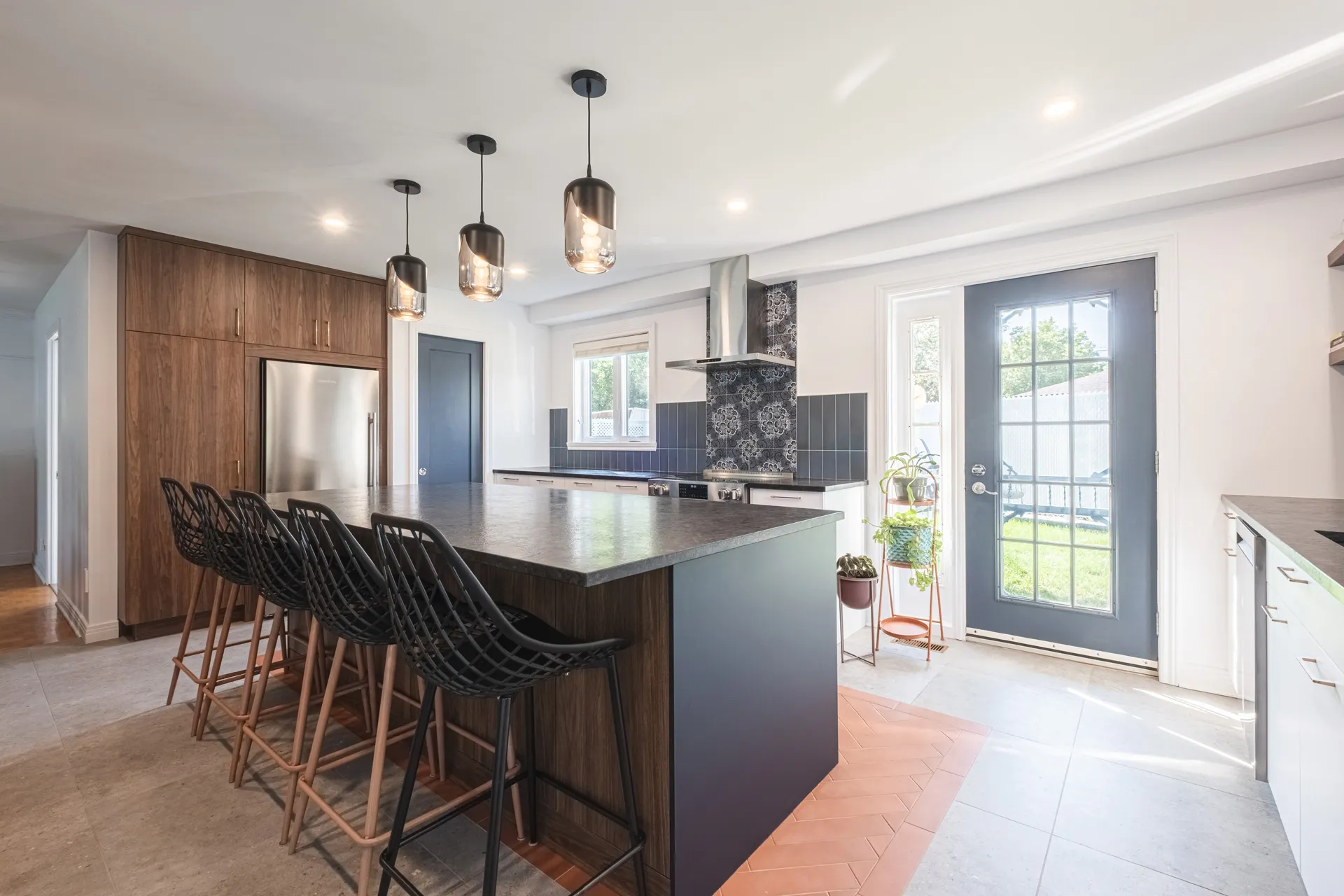 Denis Kitchen Montreal: walnut cabinets, gray island, quartz countertop, black tile backsplash, pendant lights