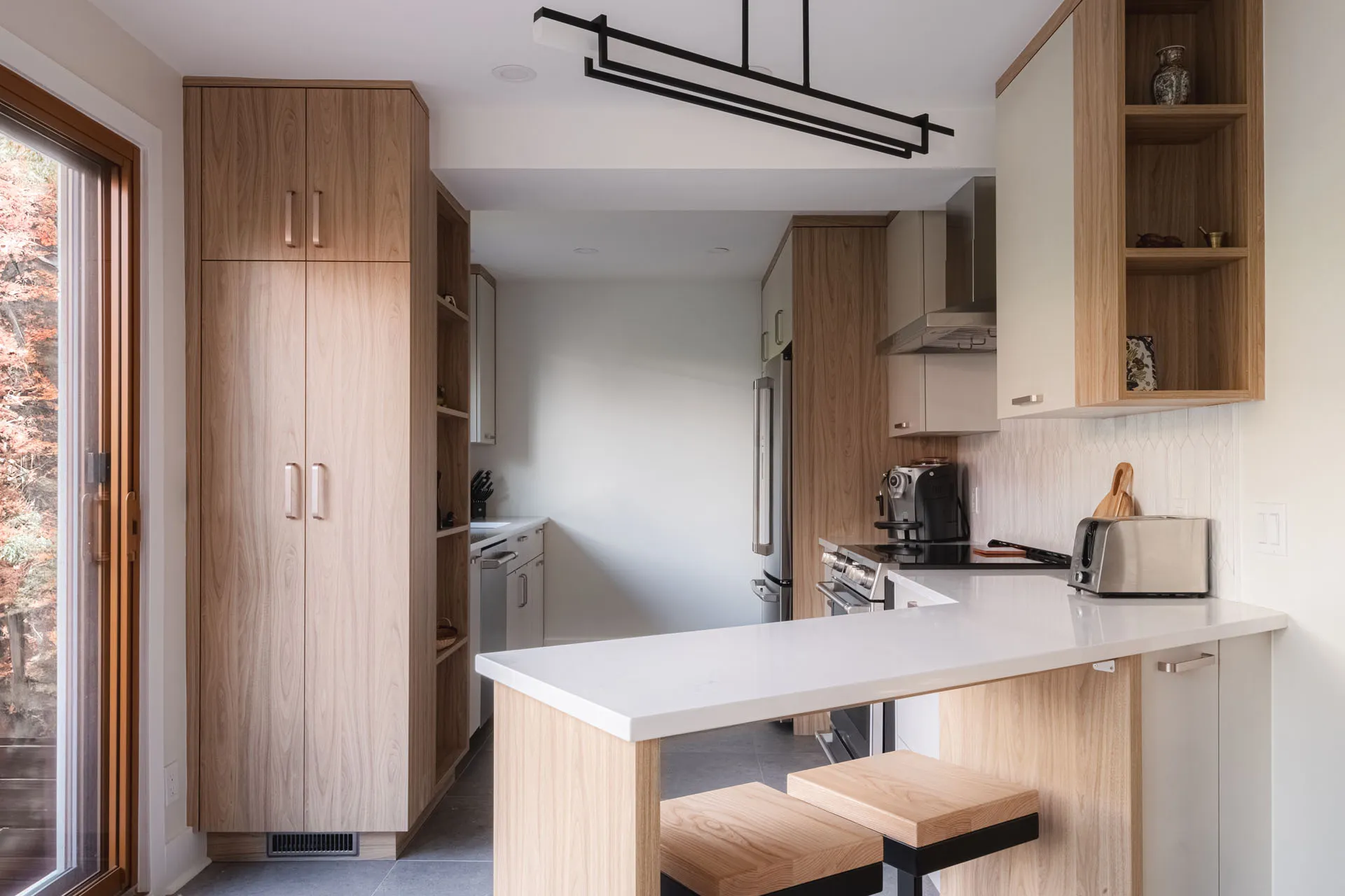 Modern Leduc-Desjardins kitchen Montreal: light oak cabinets, white countertop, island with stools, white backsplash, black pendant light