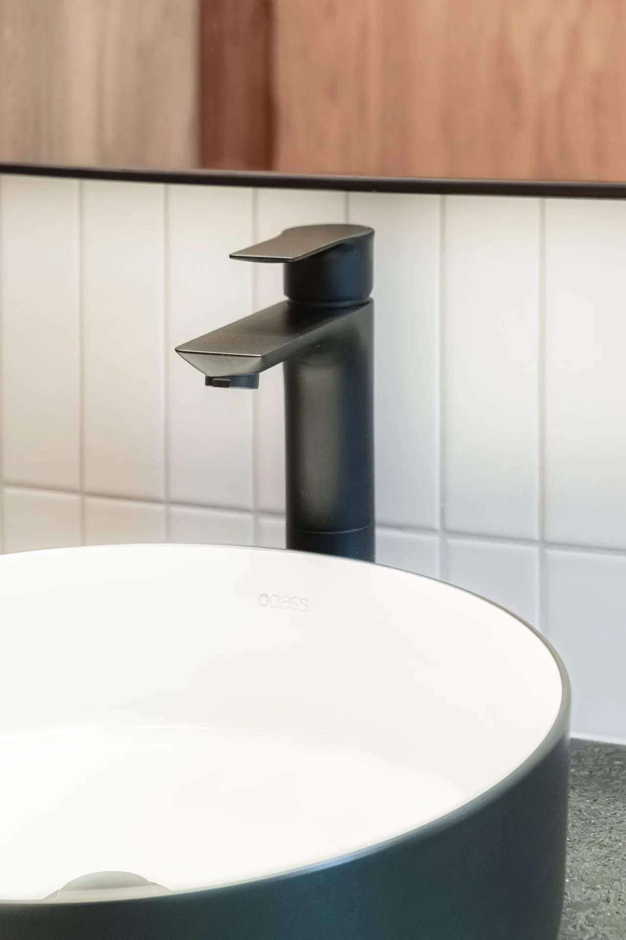 Modern bathroom with round white sink, minimalist black faucet and white subway tile backsplash with grey grout