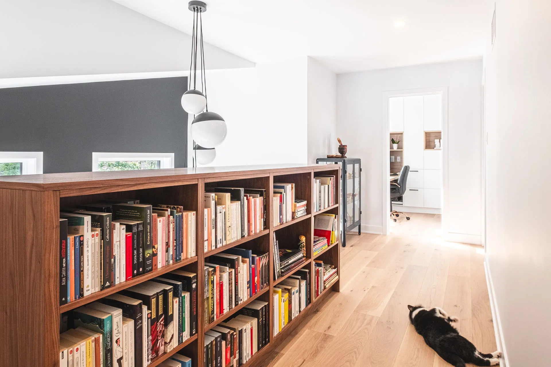 Wooden bookcase with glass doors, light flooring and modern pendant lighting in residential office