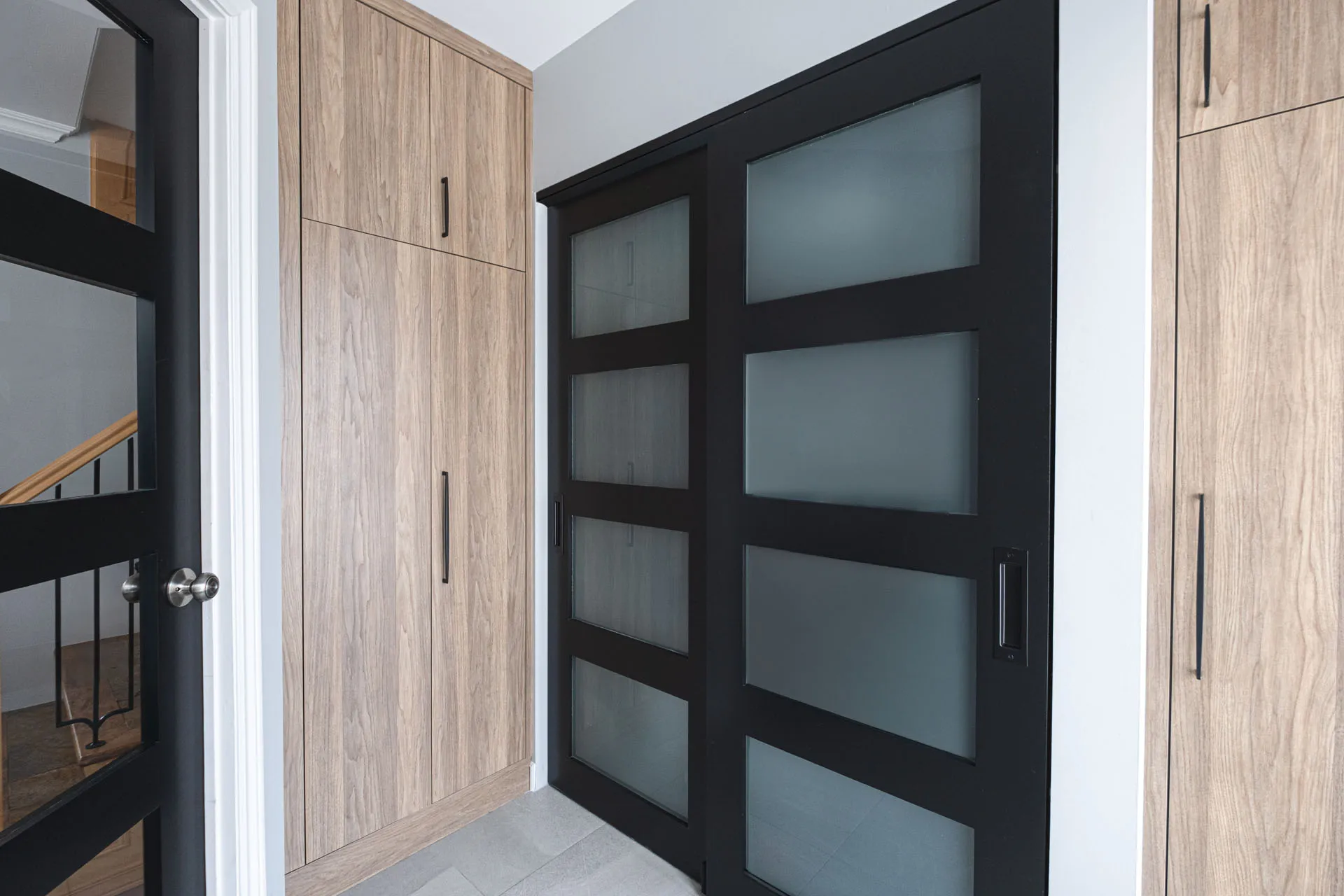 Modern hallway with light oak cabinets, black glass doors and white trim, Menuitech Boisbriand project
