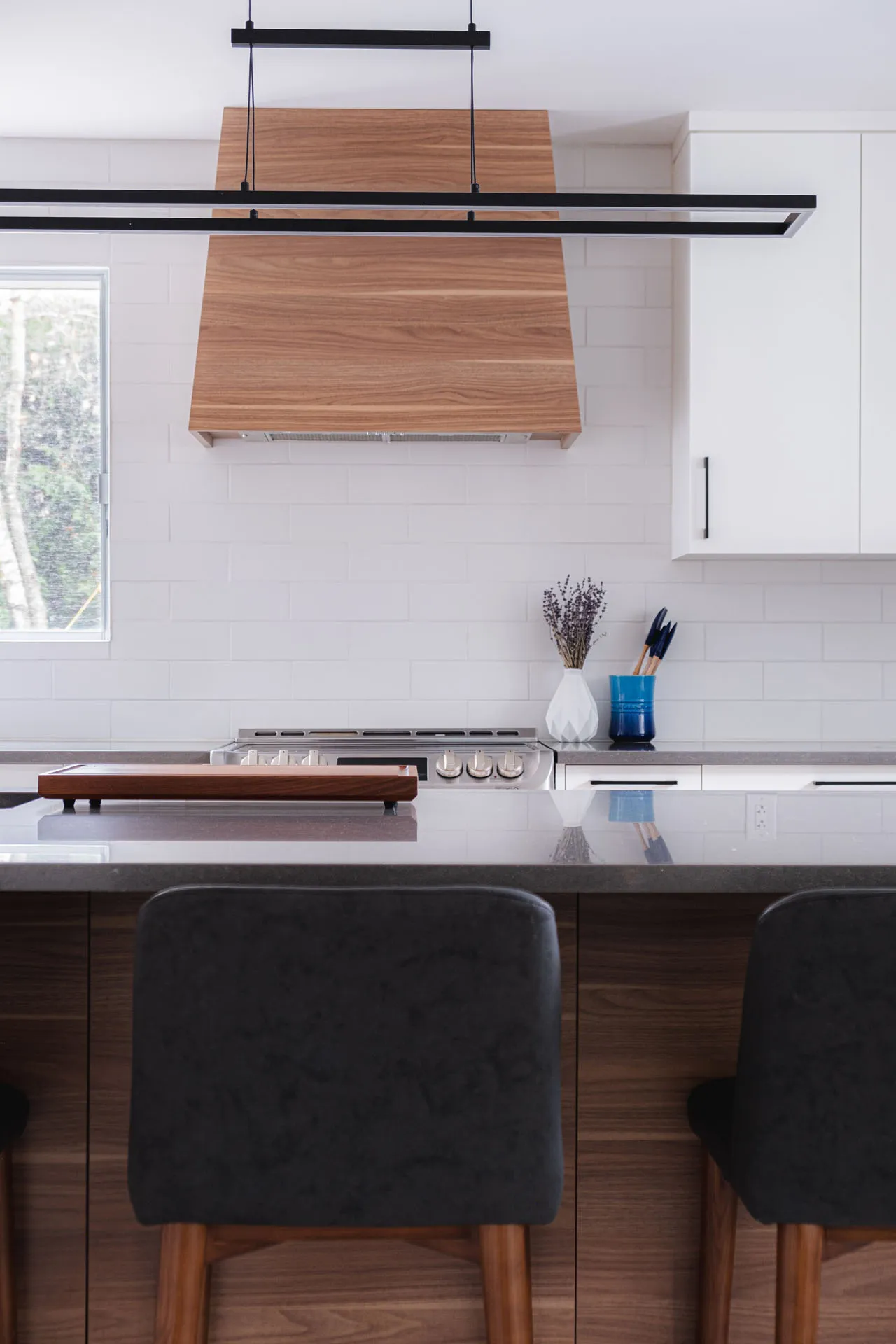 Modern Menuitech kitchen: white cabinets, wood island, gray countertop, white backsplash, black pendant light