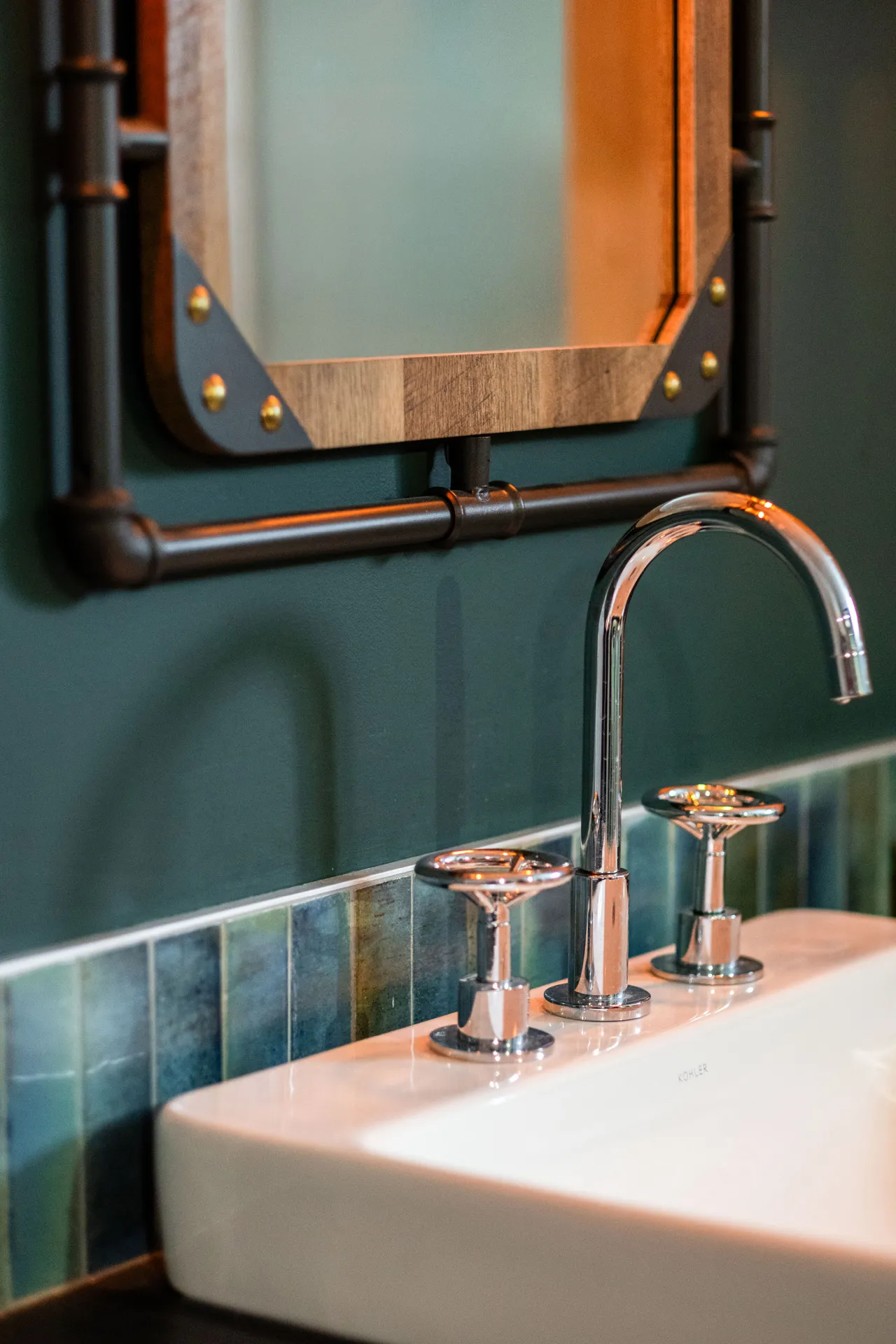 Lemay bathroom with teal cabinetry, white countertop, chrome faucet and blue-green tile backsplash