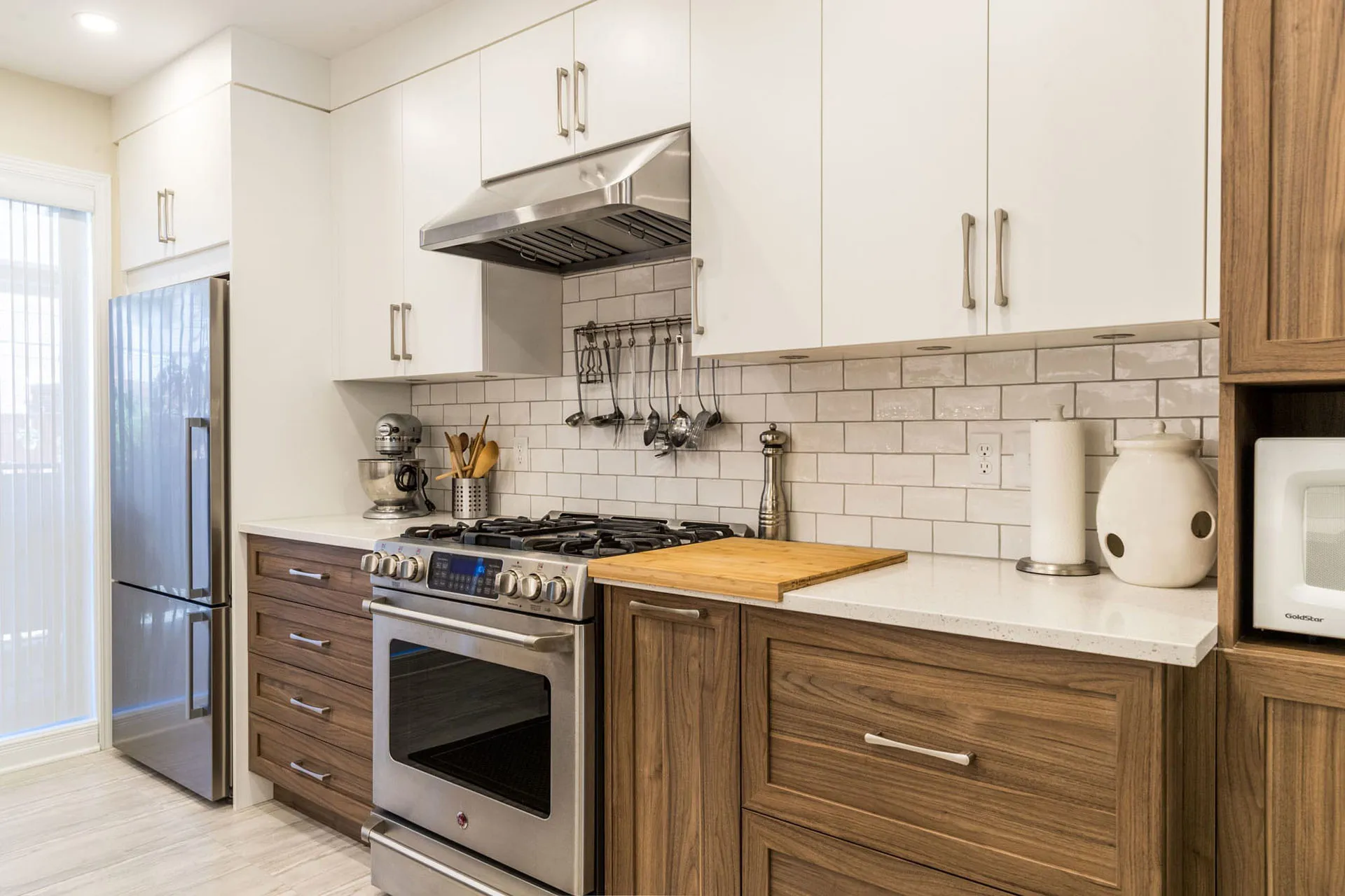 Mathieu kitchen renovation in Montreal: white and wood cabinets, white countertop, wood island, subway tile backsplash, stainless appliances