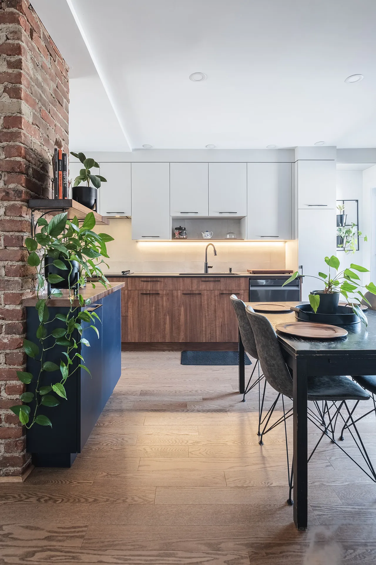 Florez Kitchen Montreal: white and wood cabinets, black countertop, blue island, beige backsplash, integrated lighting