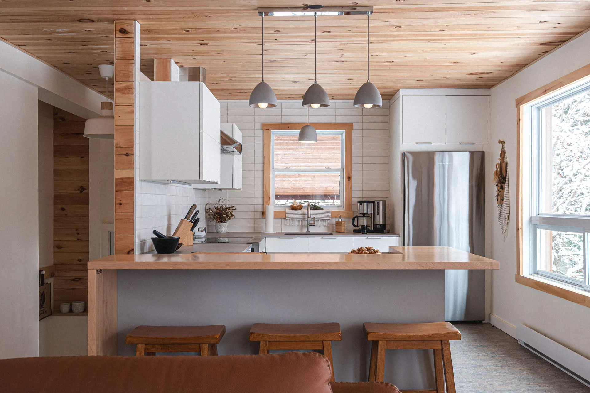White and wood kitchen with grey island, light countertop, white tile backsplash and pendant lights