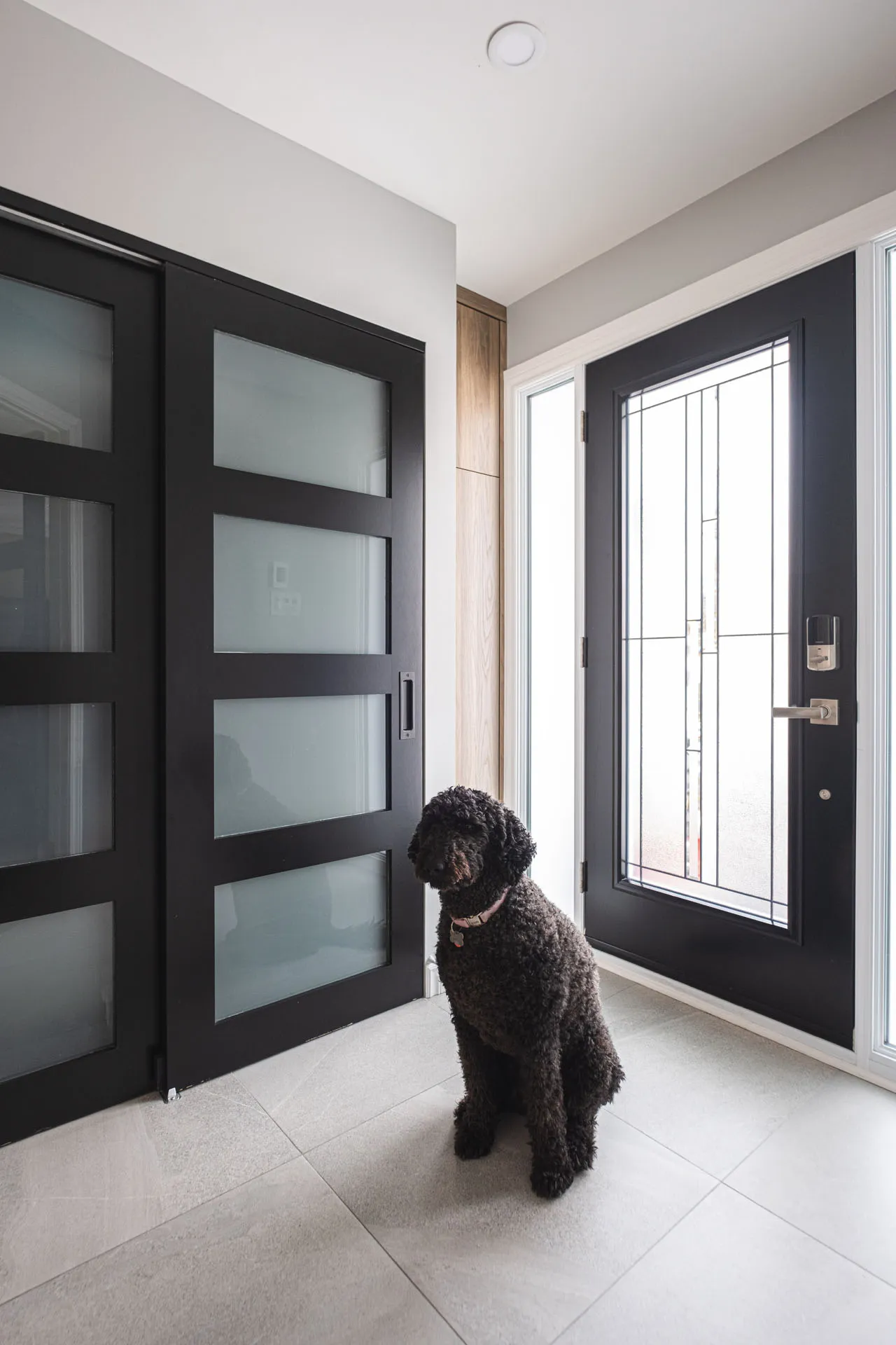 Modern entryway with black glass doors, light grey flooring and direct outdoor access - Menuitech Renovation Boisbriand