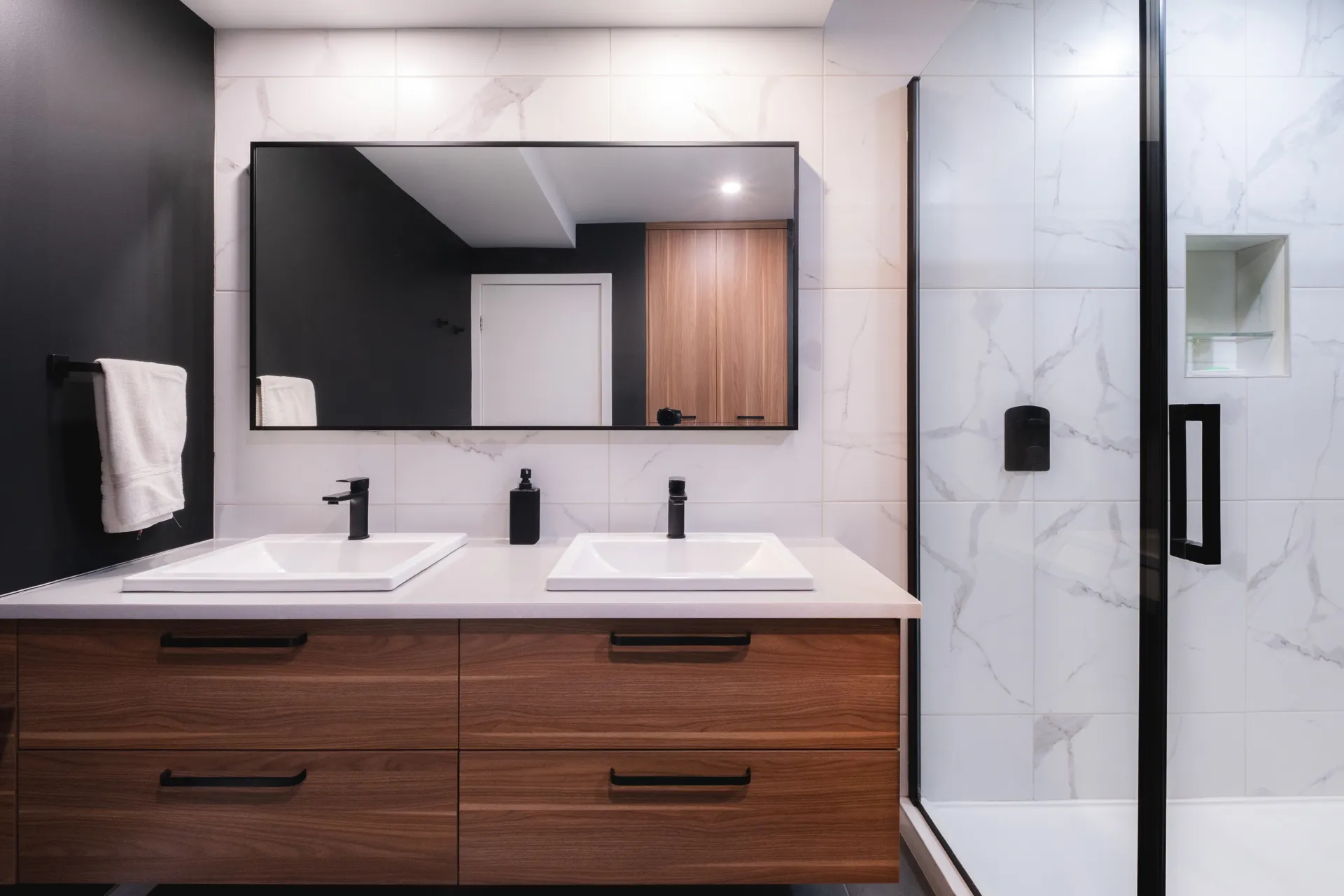 Salle de bain Gratton-Bellefeuille: vanité en bois noyer, comptoir blanc, miroir encadré noir, dosseret marbre, double lavabo