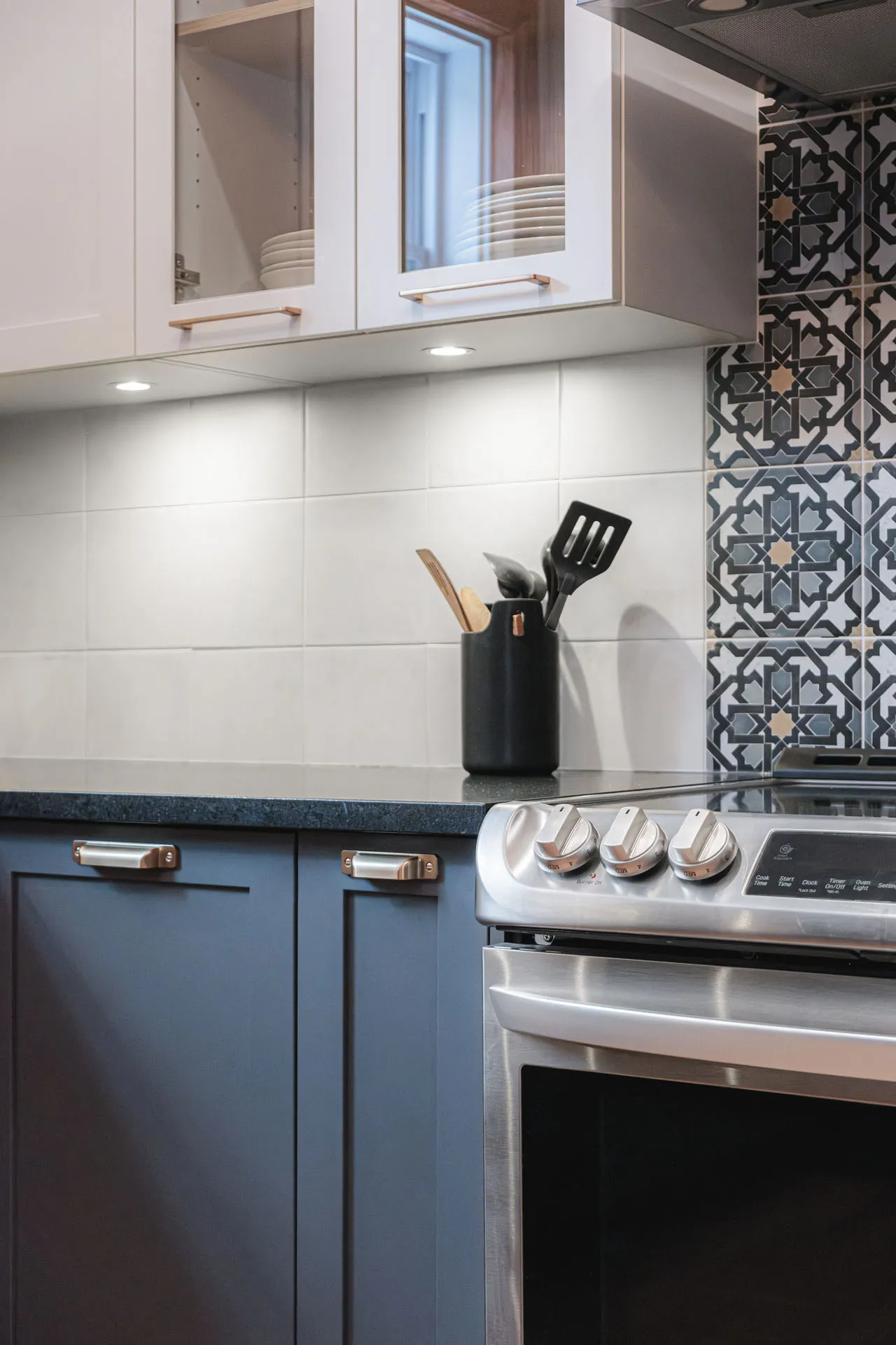 Stephan kitchen Montreal: white and blue cabinetry, black countertop, geometric tile backsplash, stainless steel appliances