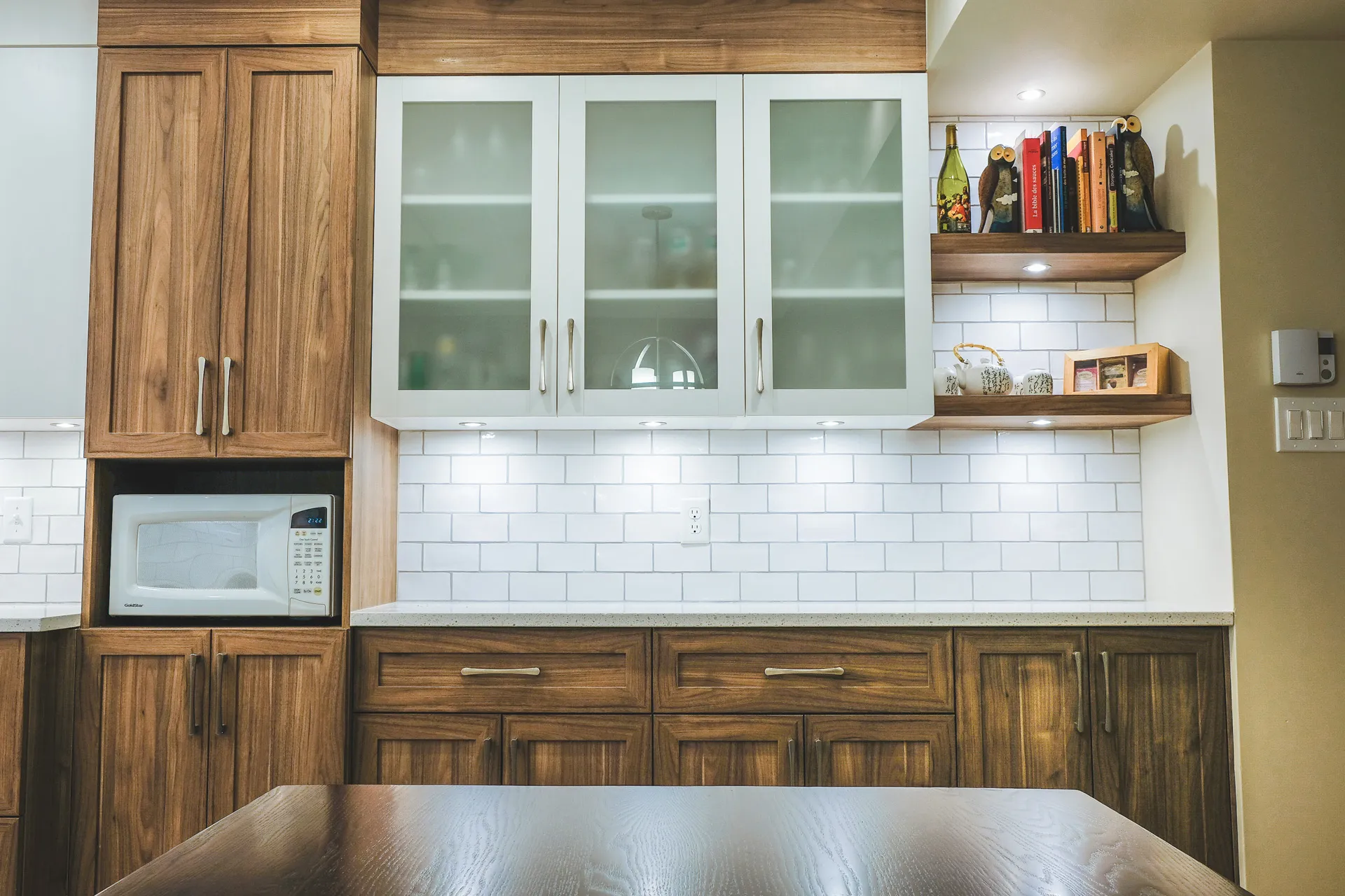 Mathieu kitchen Montreal: white and walnut wood cabinets, grey countertop, white subway tile backsplash, floating shelves