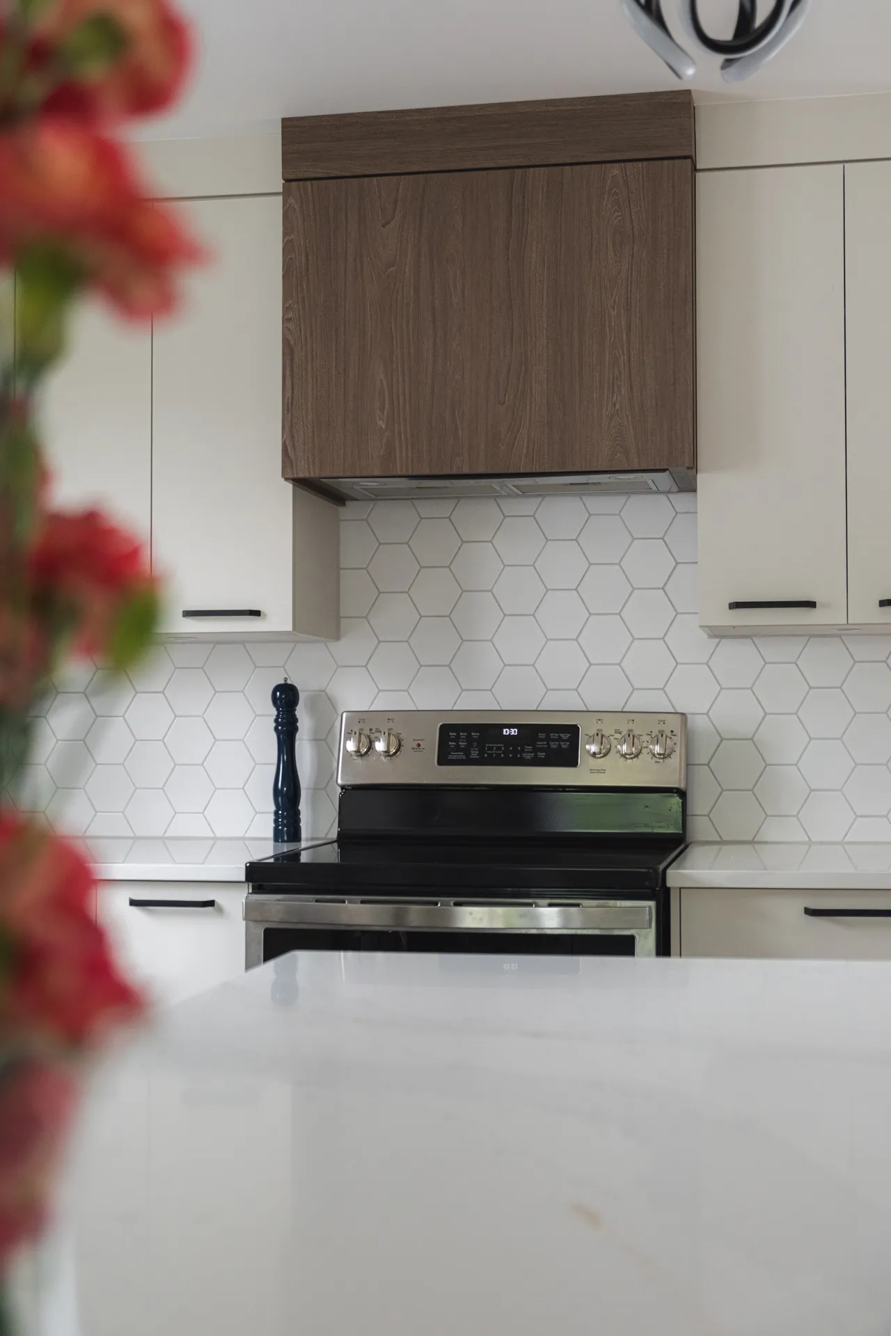 Modern Barrett-Toth kitchen: white and dark wood cabinets, white countertop, hexagonal backsplash, stainless steel range