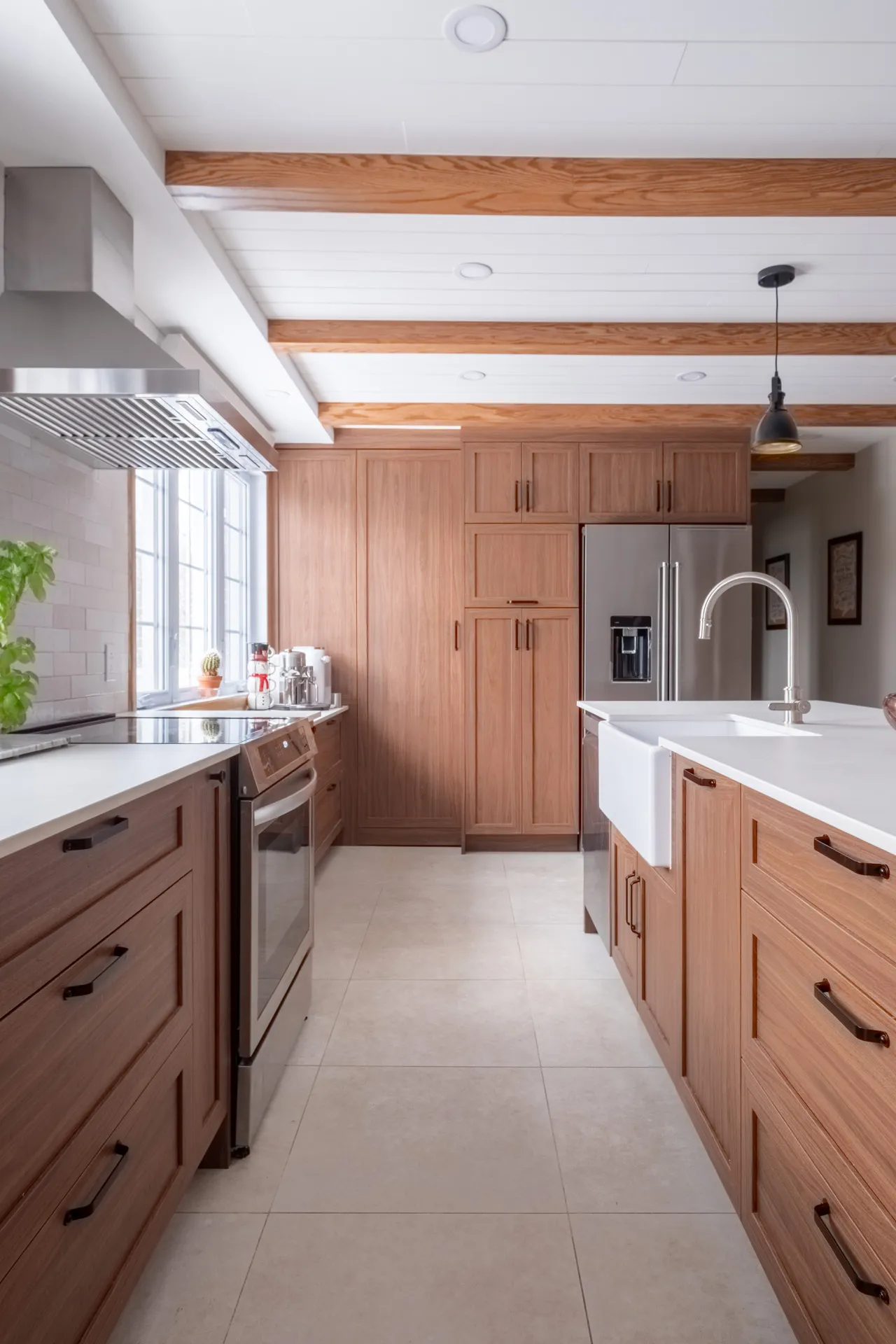 Menuitech Lemay kitchen: oak cabinets, white countertops, island with farmhouse sink, exposed beams, white subway tile backsplash