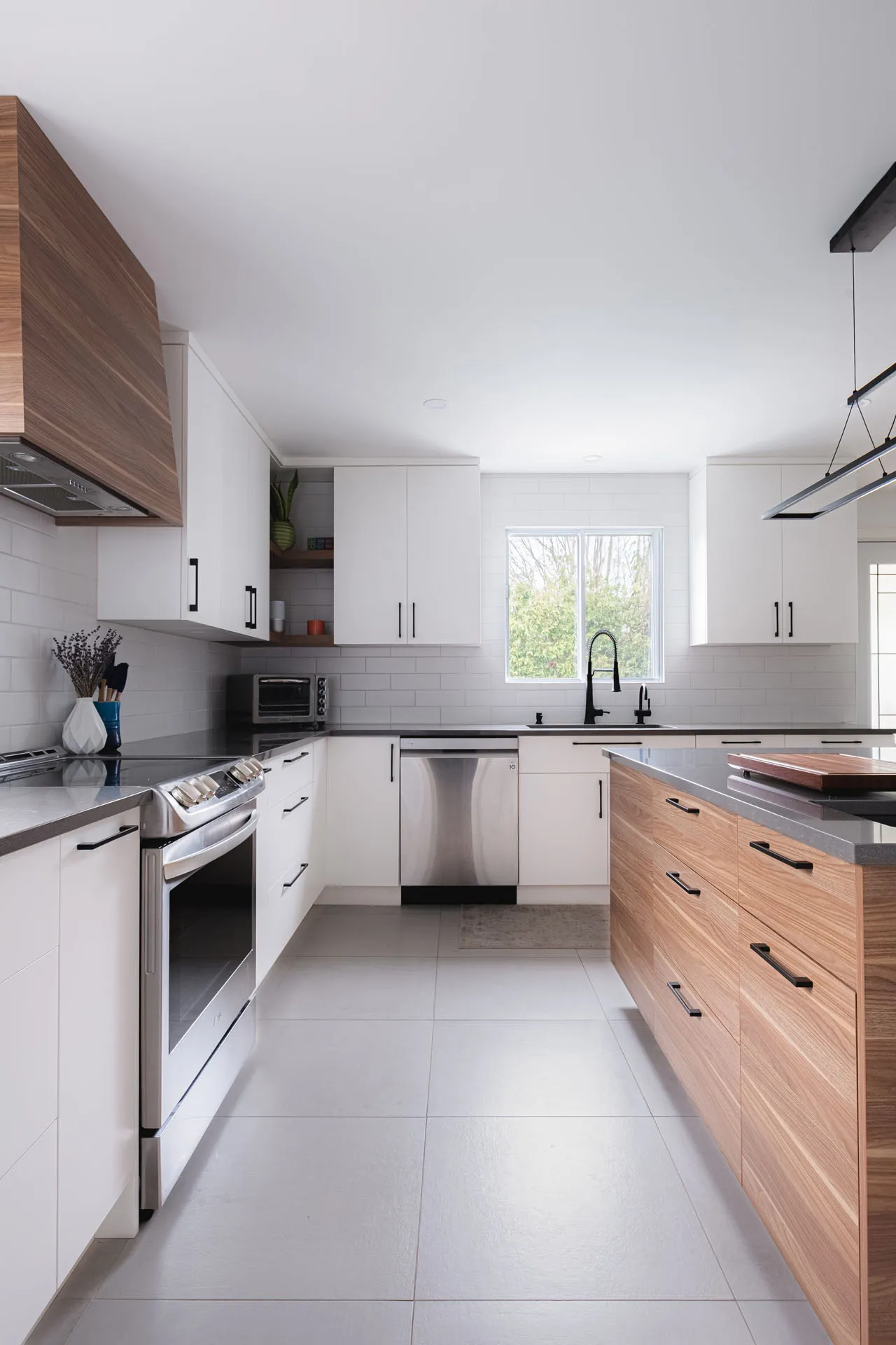 Modern Menuitech kitchen with white and wood cabinets, grey countertop, wood island, white subway tile backsplash, Montreal