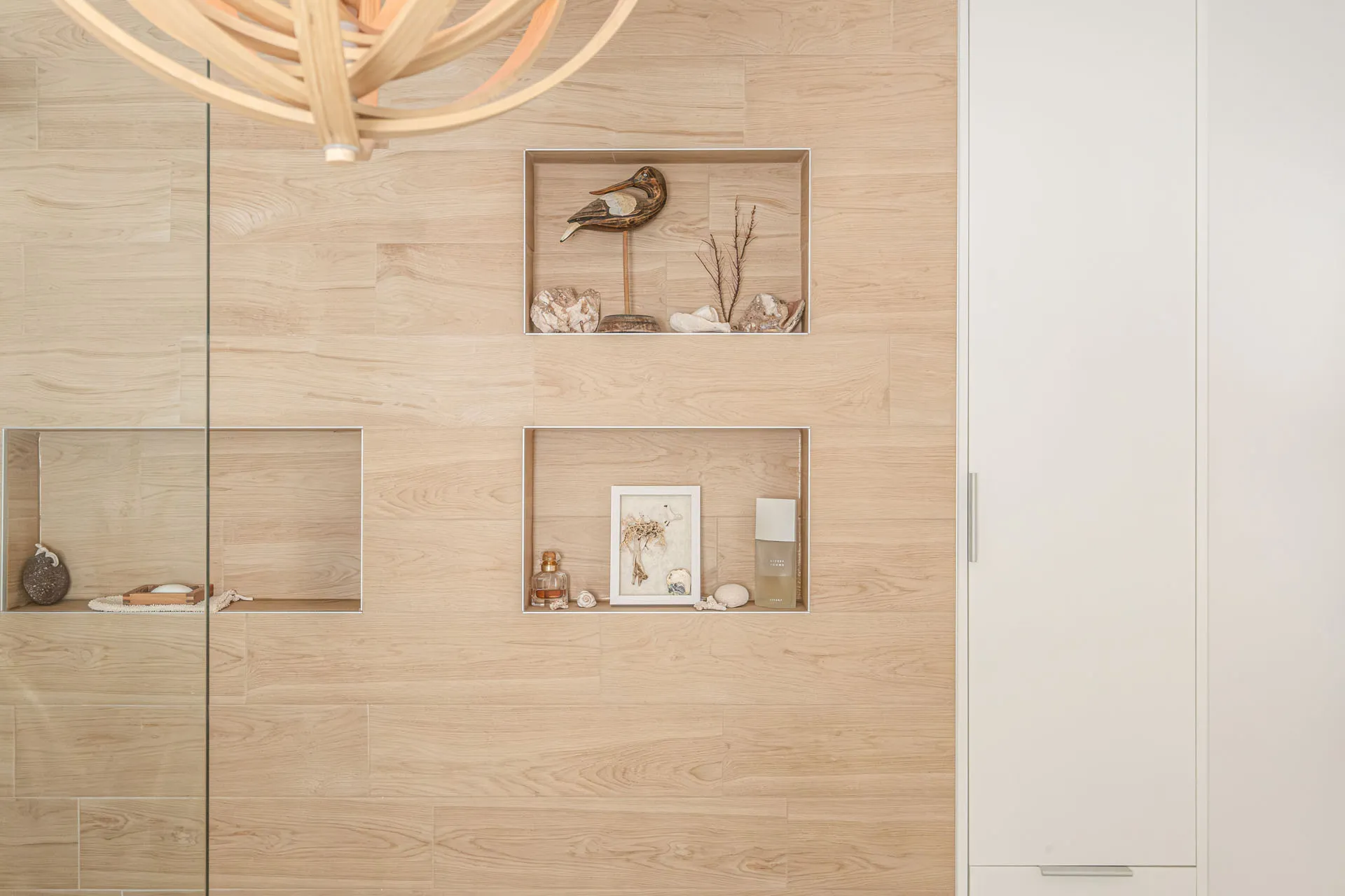 Modern bathroom with light wood wall niches, beige tile, minimalist accessories and pendant lighting fixture