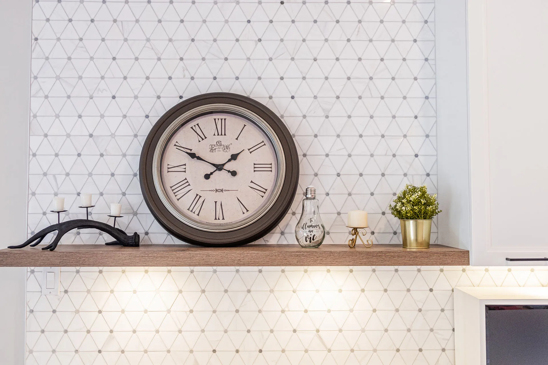 Simard kitchen: wooden countertop, geometric grey tile backsplash, minimalist décor with wall clock.