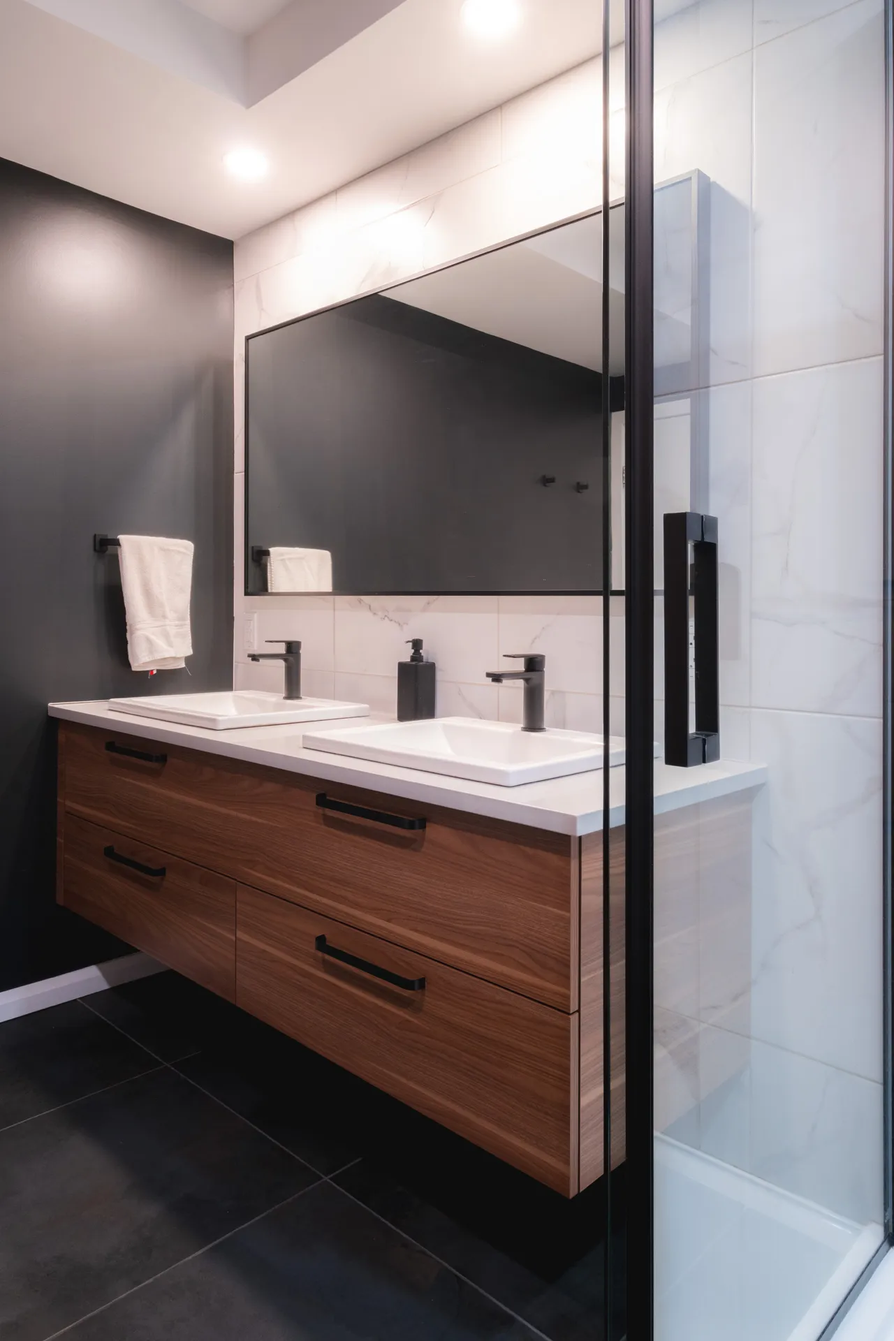 Salle de bain moderne avec vanité en bois massif, comptoir blanc, miroir encadré noir et douche vitrée, Menuitech