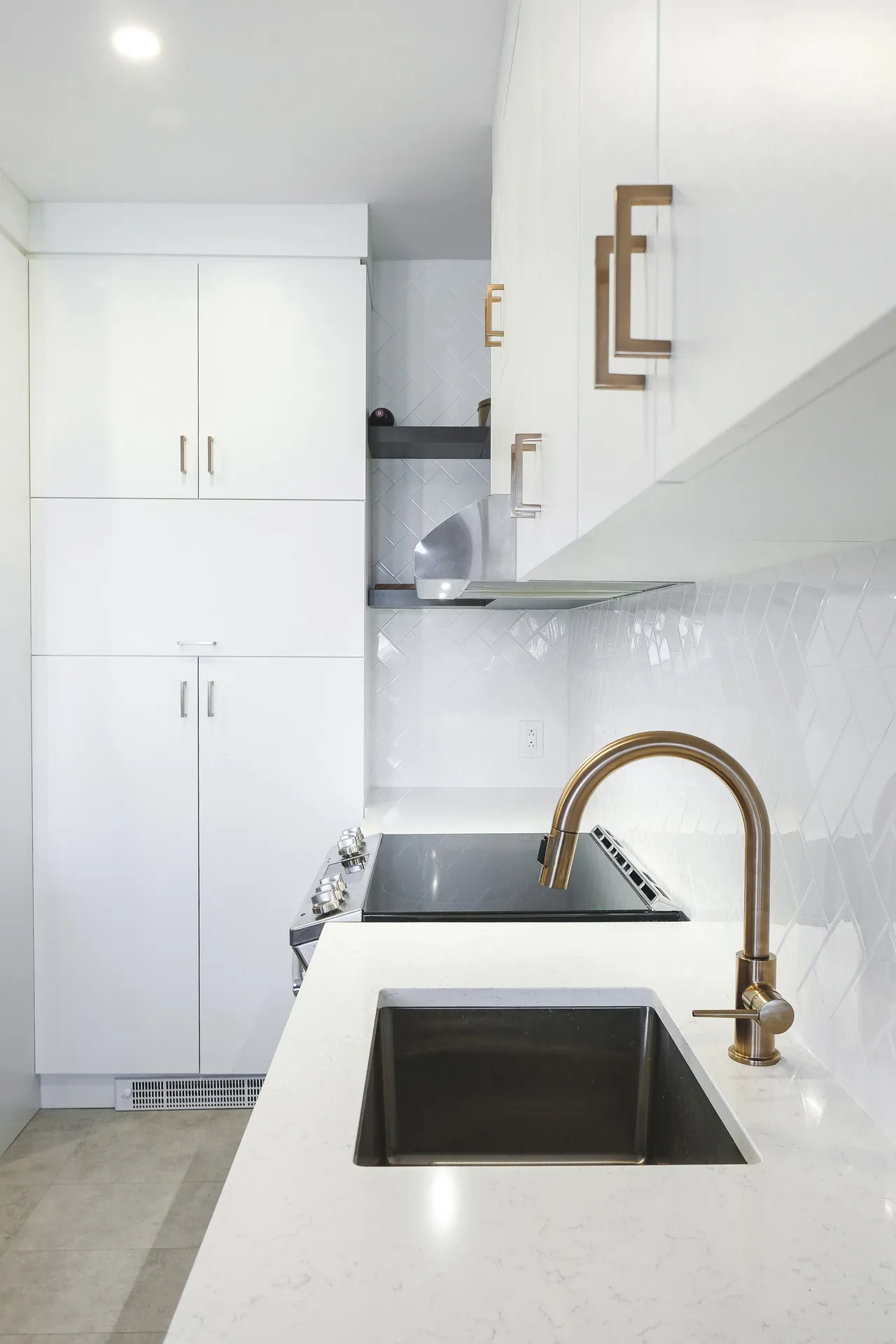 Modern Cavanagh kitchen: white cabinets, white countertop, island with black sink, white tile backsplash, bronze faucet