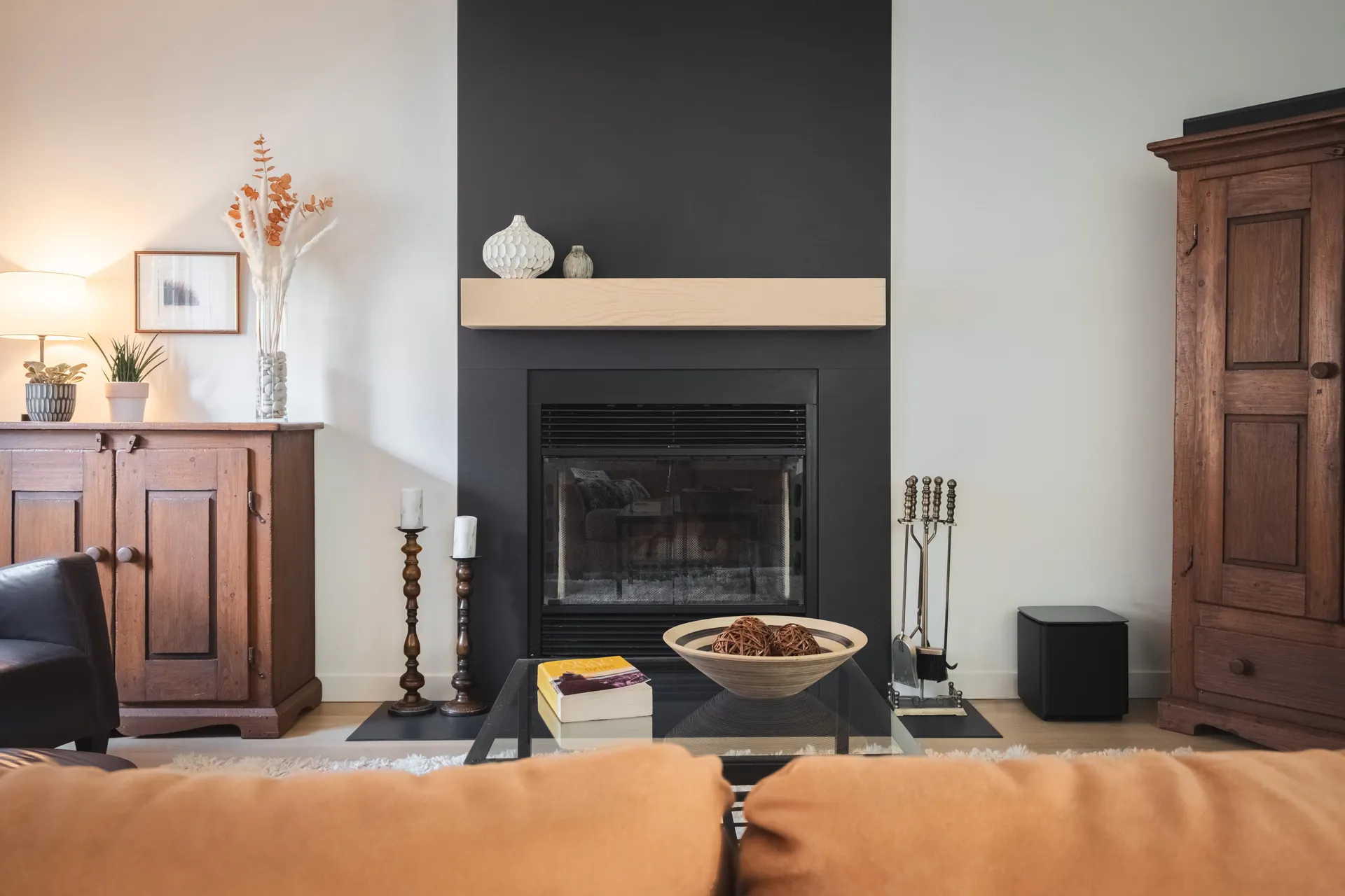 Salon moderne avec foyer encastré, mur d'accent gris, manteau bois clair, meubles en noyer et décoration minimaliste