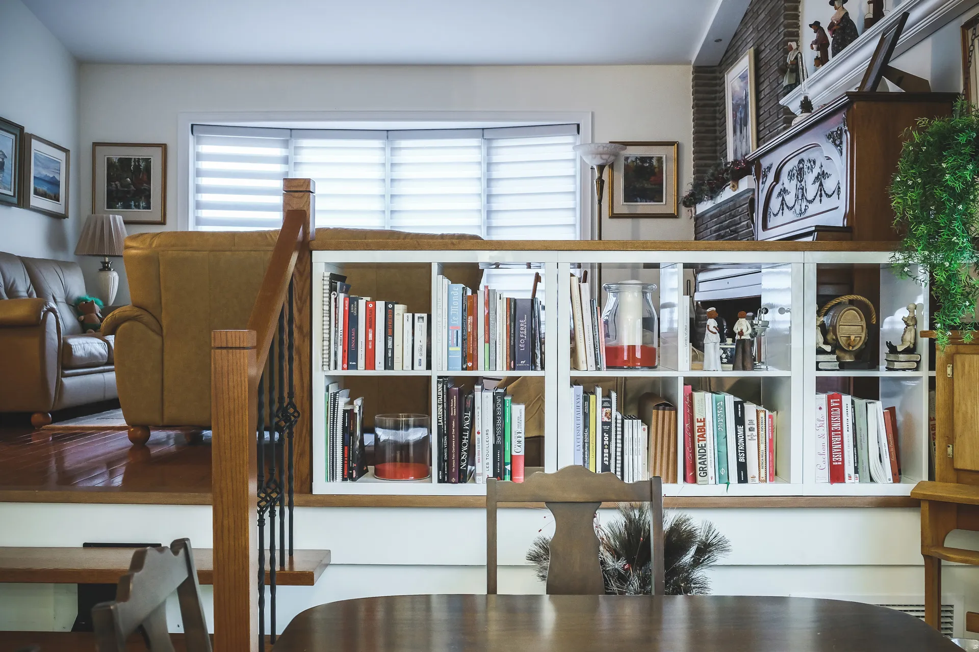 White wall-mounted bookcase with glass cabinets, books and decor in modern residential living room style