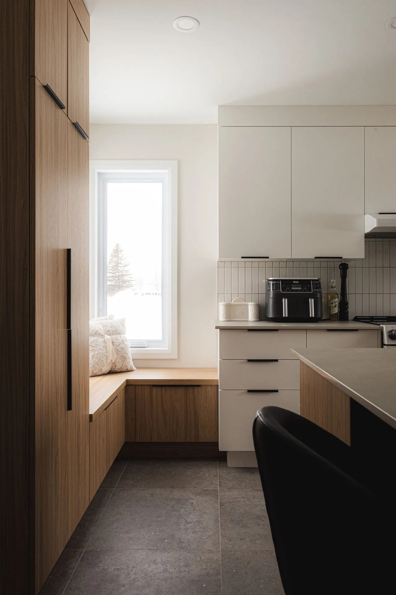 Modern Menuitech kitchen with light wood and cream white cabinetry, gray countertop, subway tile backsplash, panoramic window