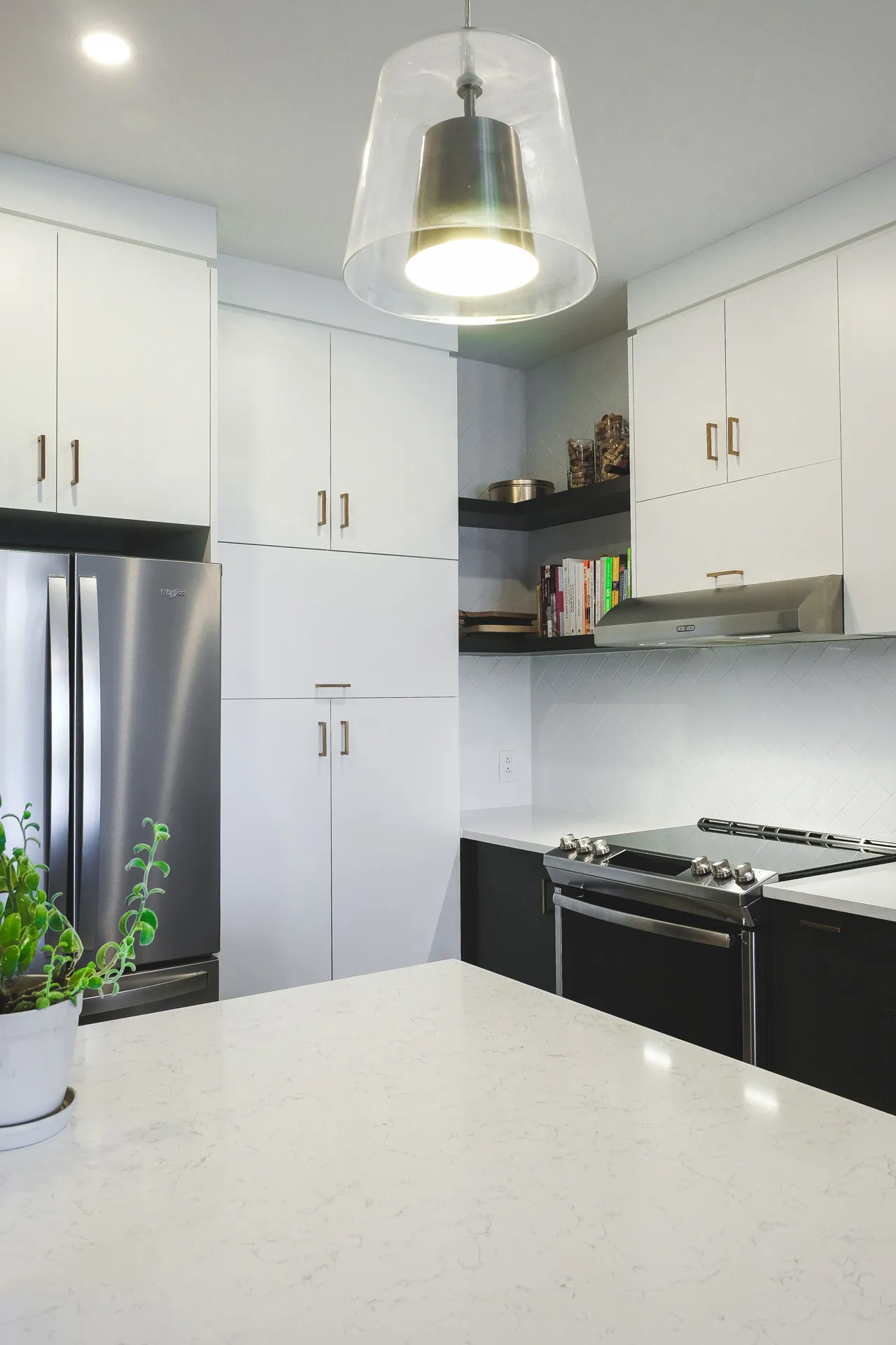 Modern Cavanagh kitchen: white lacquered cabinets, marble countertop, black island, tile backsplash, glass pendant light.