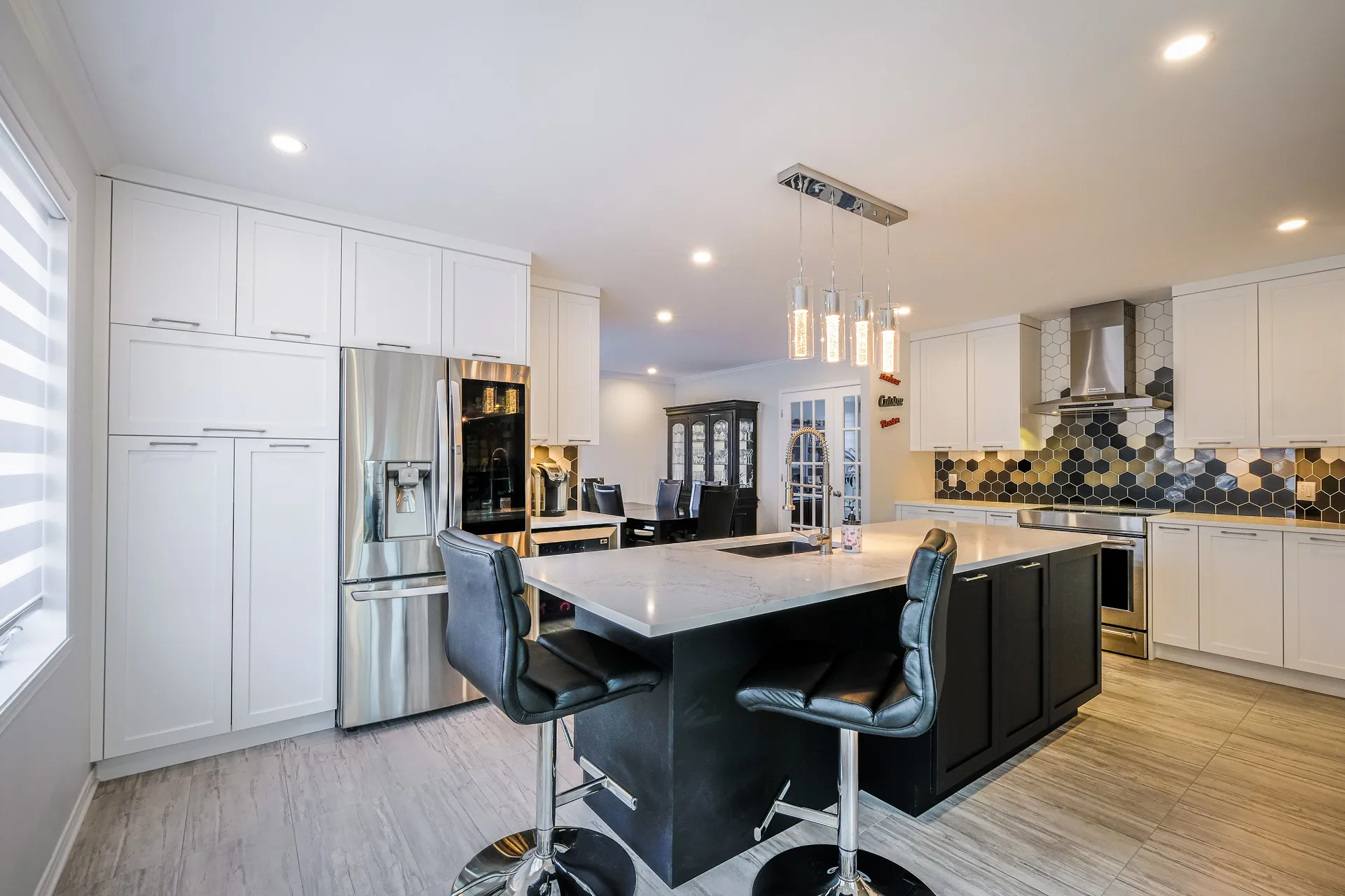 Landry kitchen Boisbriand: white cabinets, black island with white marble countertop, black hexagonal backsplash, stainless steel appliances