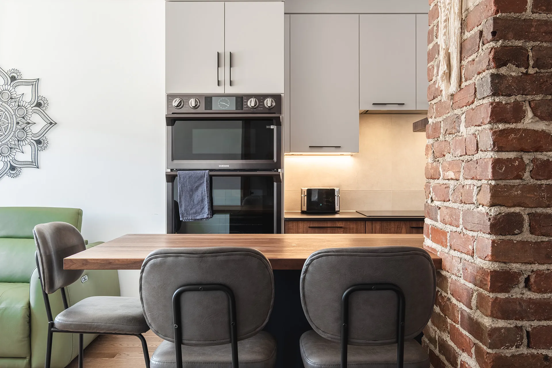 Florez Montreal kitchen: grey cabinets, wood countertop, island, backlit backsplash, integrated appliances