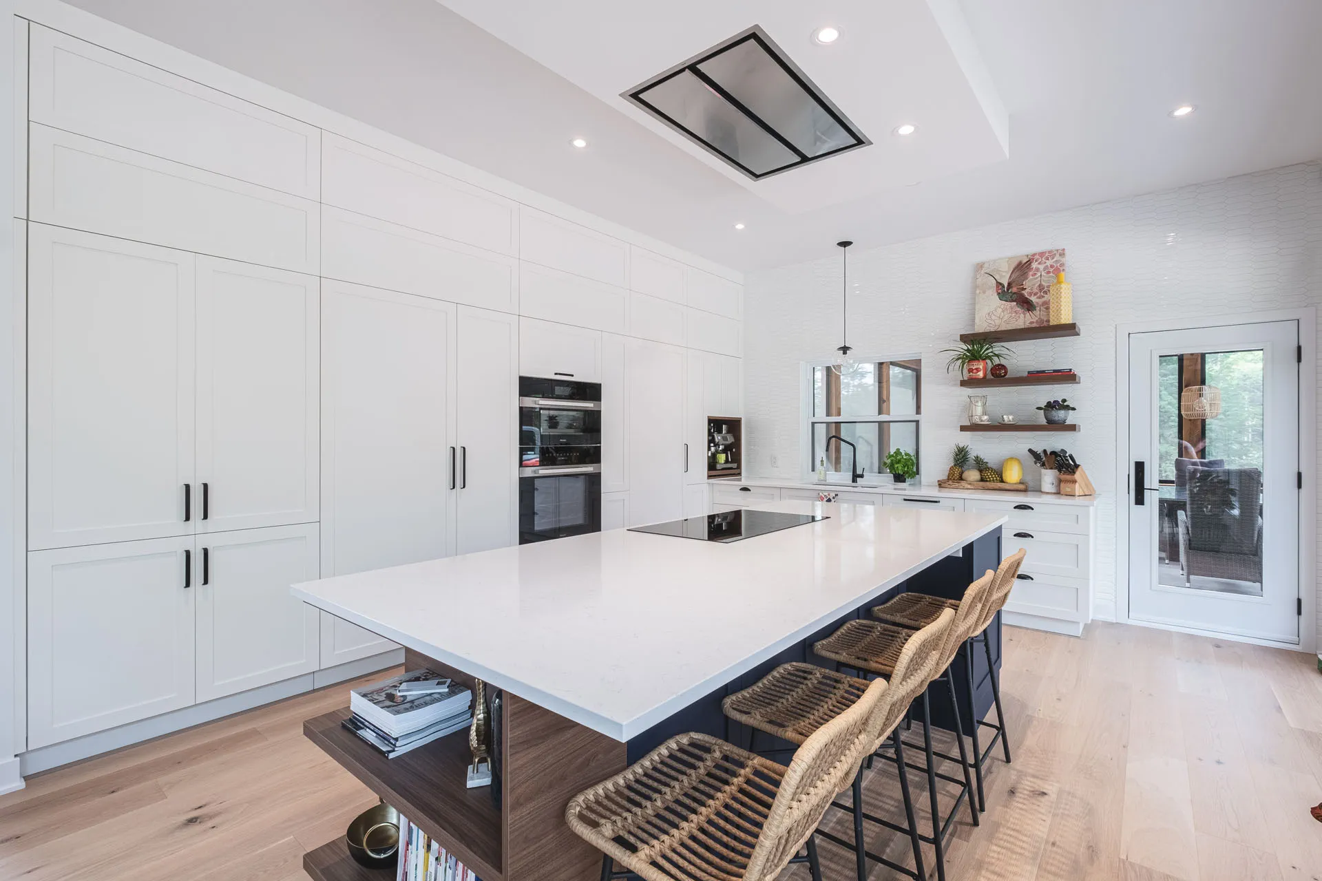 White kitchen with black island, white countertop, custom Menuitech cabinets, white backsplash, open shelving.