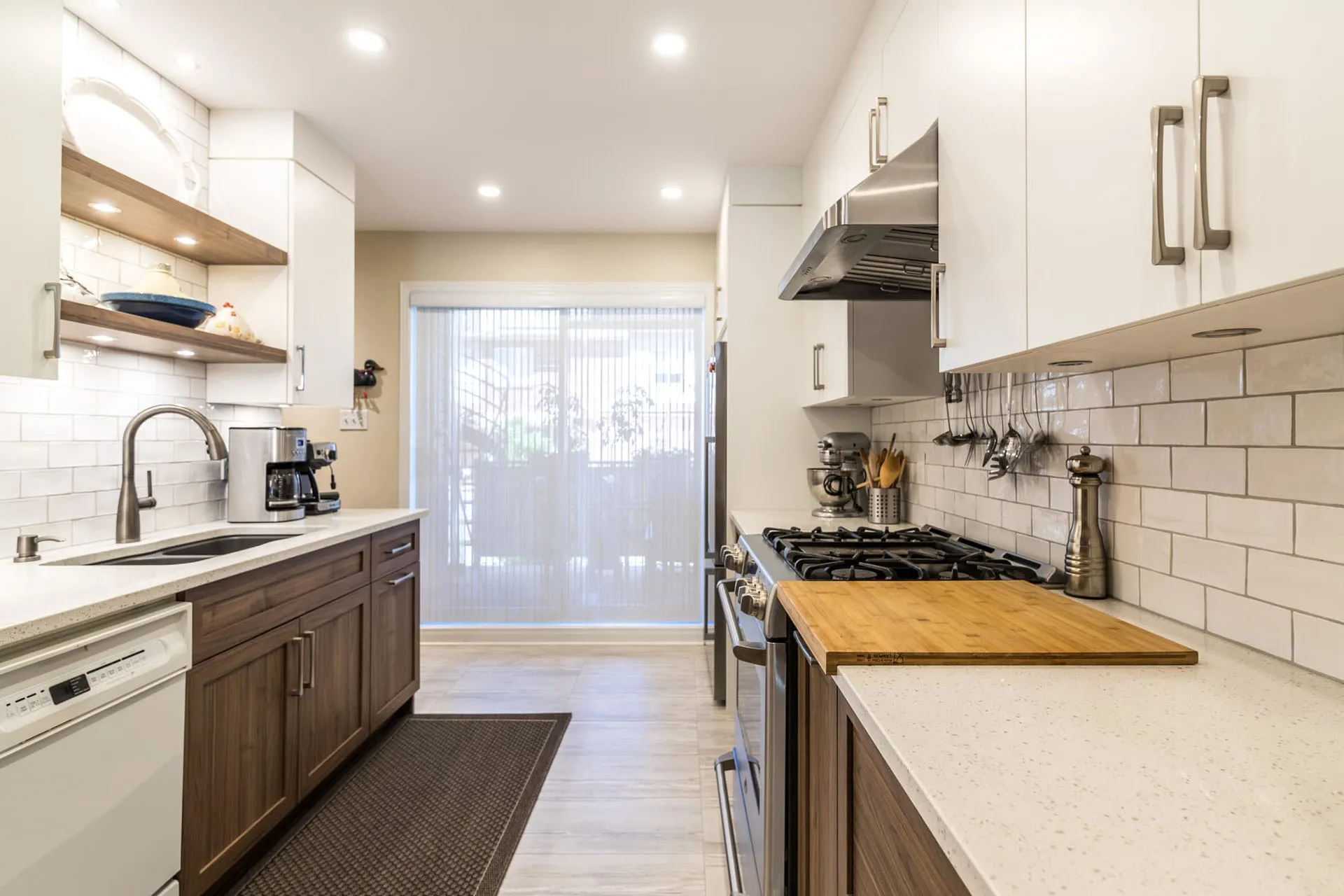 Mathieu Kitchen Montreal: white and dark wood cabinets, off-white countertop, island with wood top, white subway backsplash, stainless steel appliances.