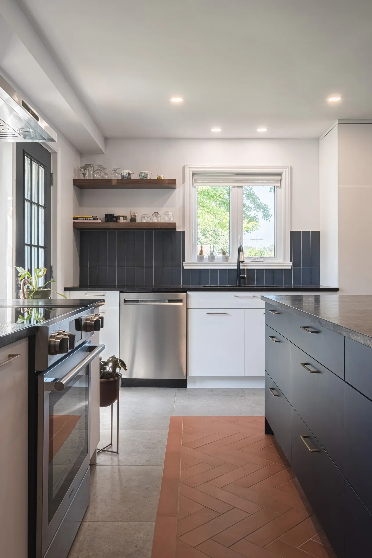 Modern Denis kitchen in Montreal: white and grey cabinets, black countertops, black tile backsplash, island, window