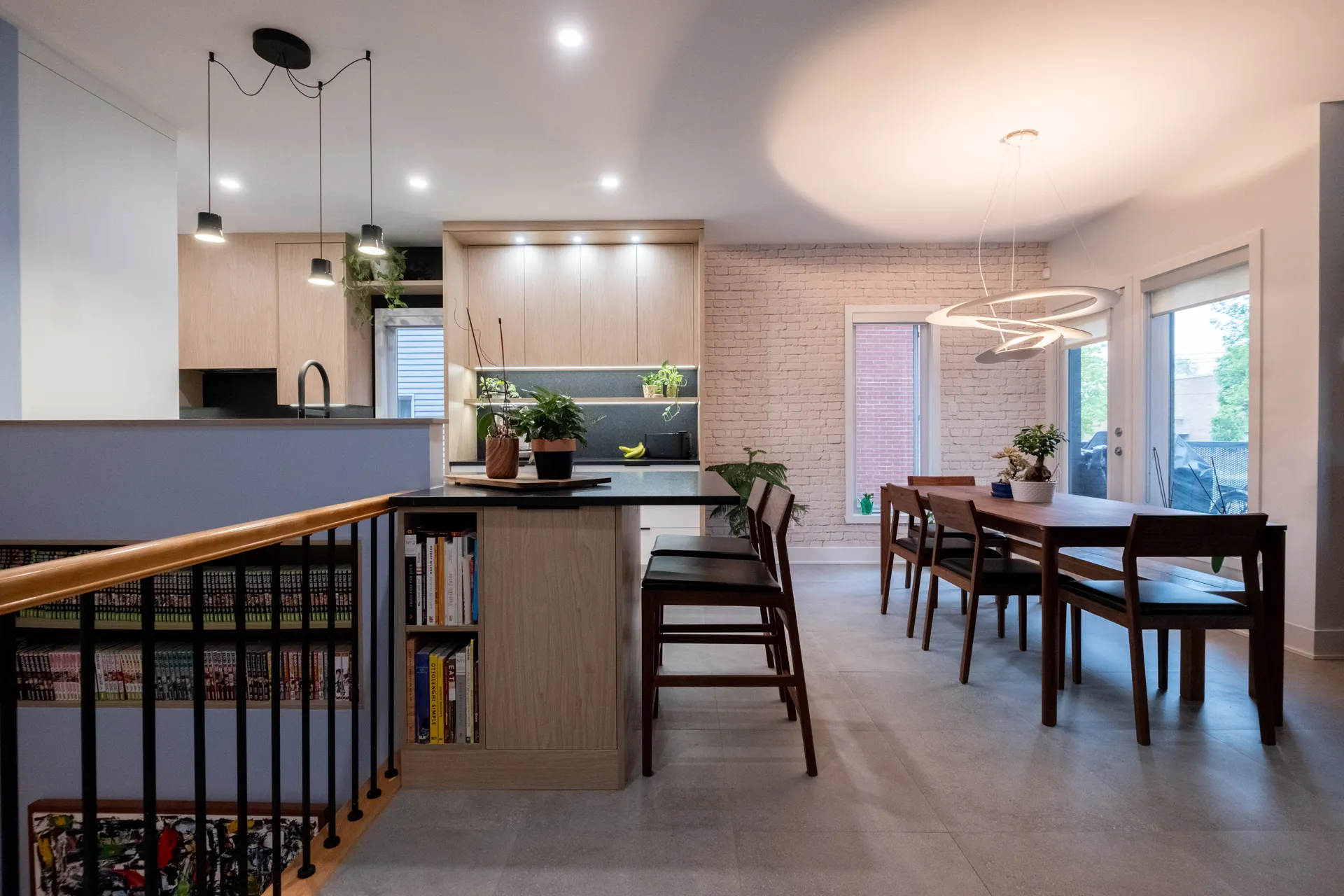 Cuisine moderne Menuitech avec armoires chêne clair, comptoir noir, îlot central, dosseret gris ardoise, luminaires suspendus