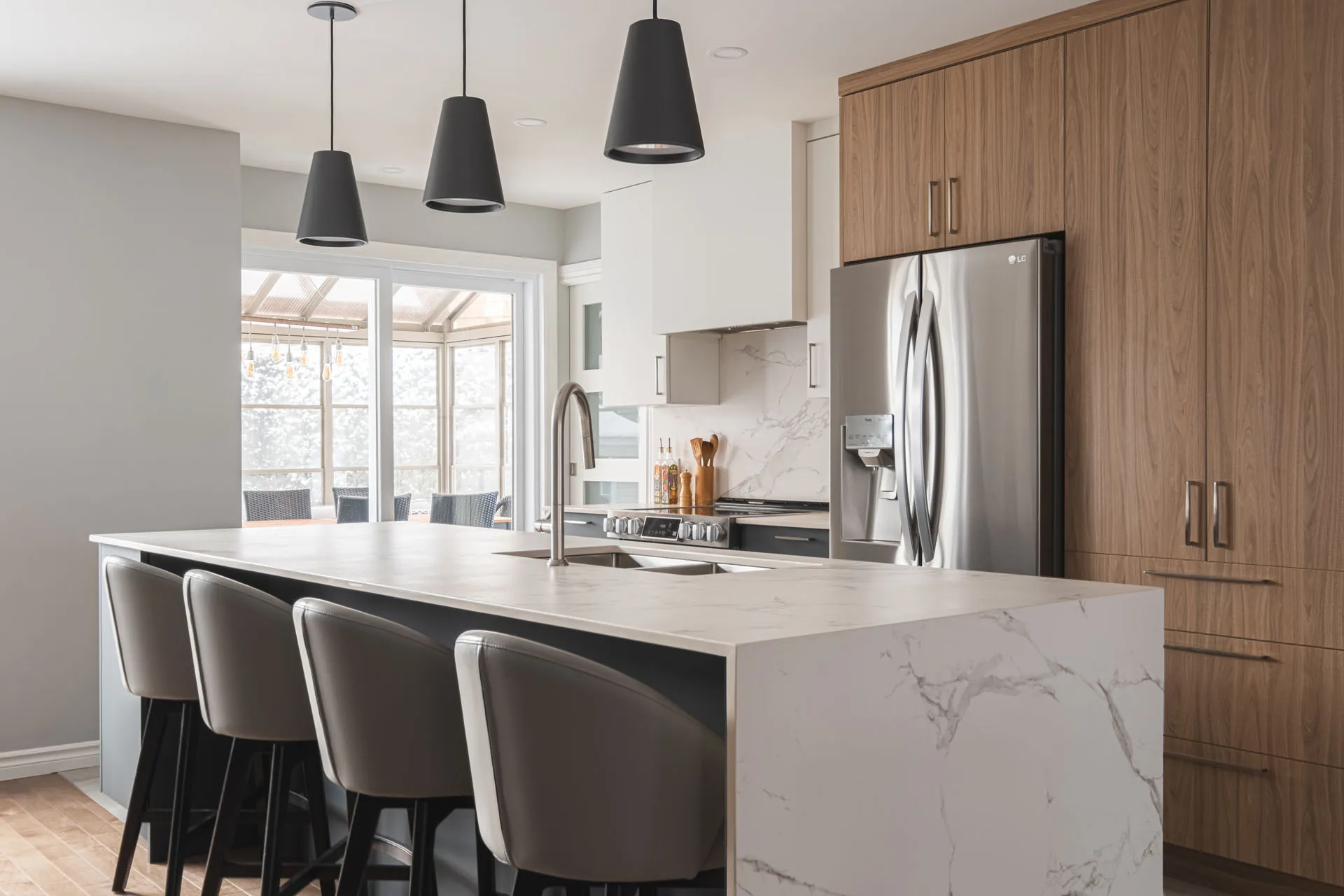 Modern Landry D'Amours kitchen: walnut cabinets, white marble countertop, island, marble backsplash, black pendant lights
