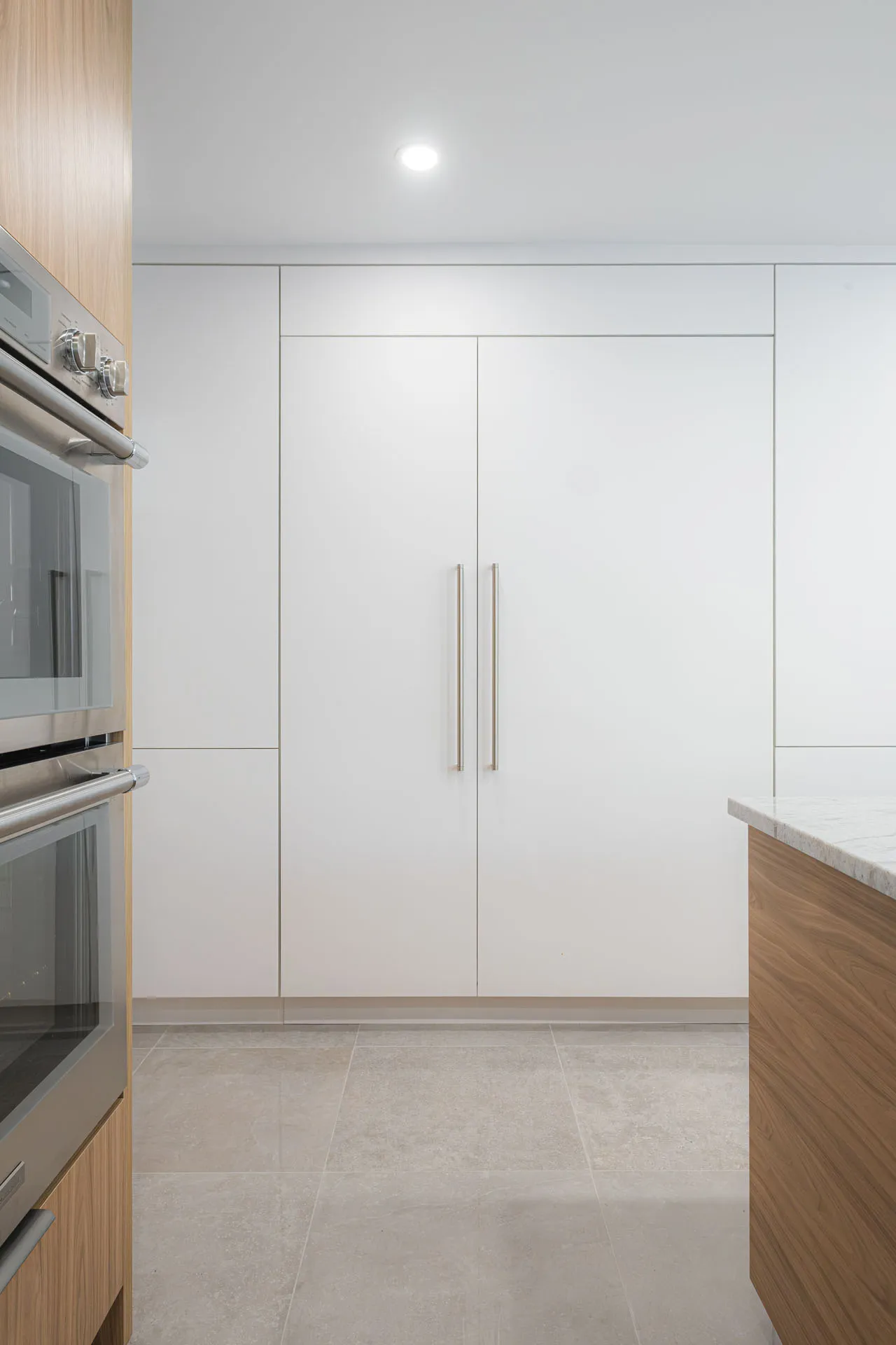 Cuisine moderne Rosemère : armoires blanches laquées, façades bois naturel, comptoirs blancs, îlot bois, appareils acier inoxydable