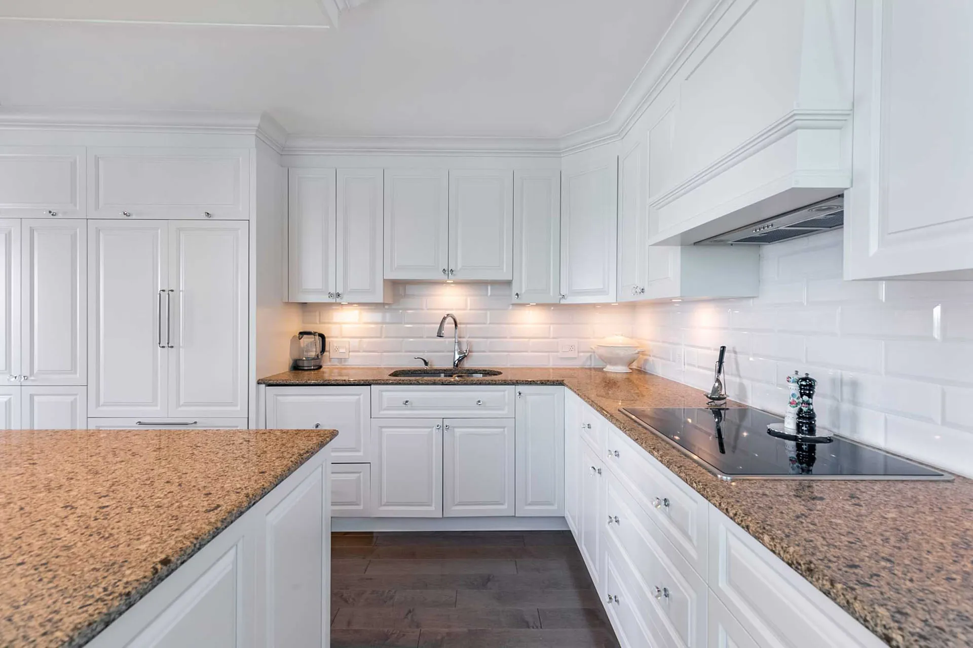 White Menuitech kitchen with granite countertops, white tile backsplash, central island and integrated lighting