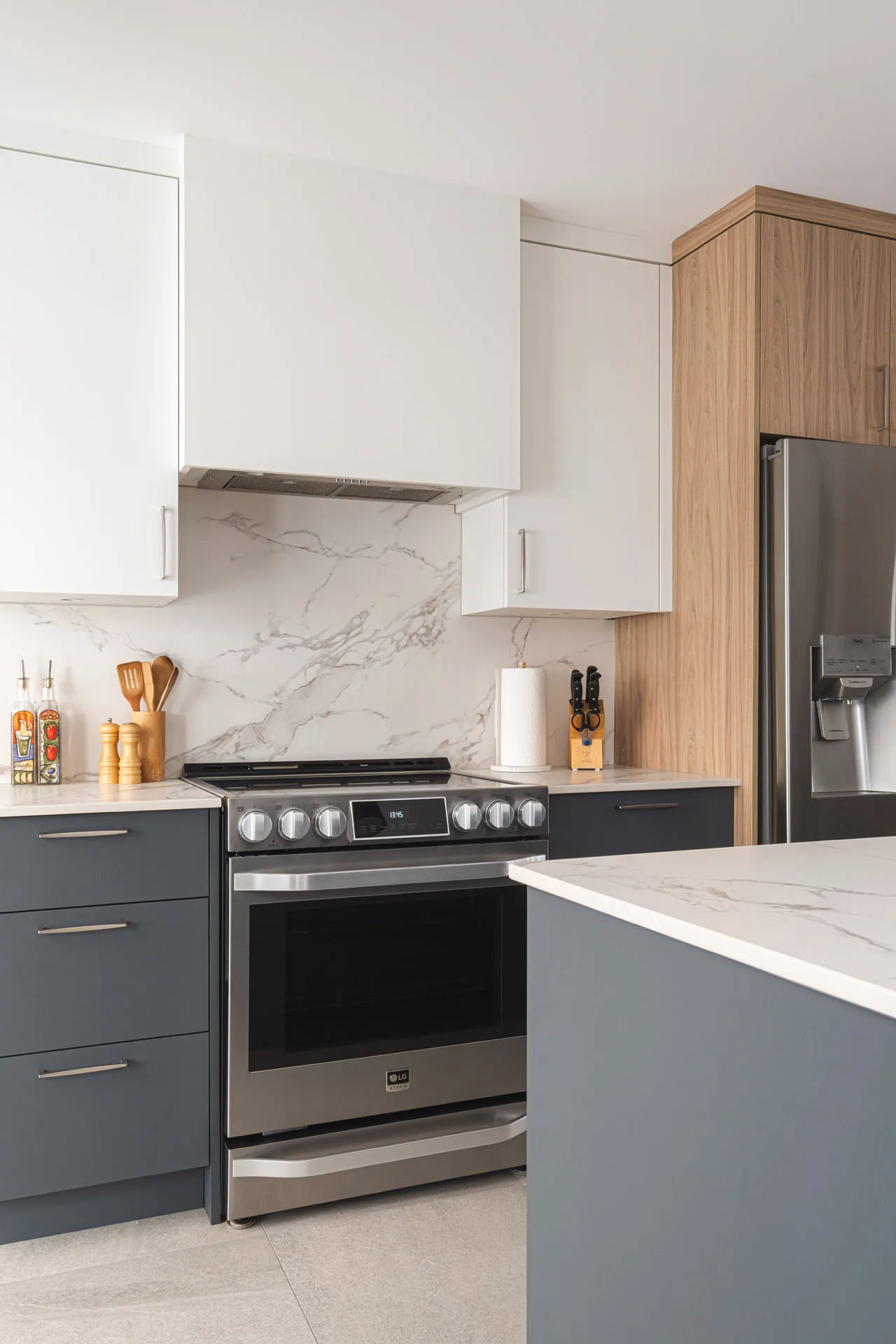 Modern Landry-D'amours kitchen: charcoal grey and white cabinets, marble countertop, island, marble backsplash, stainless steel appliances